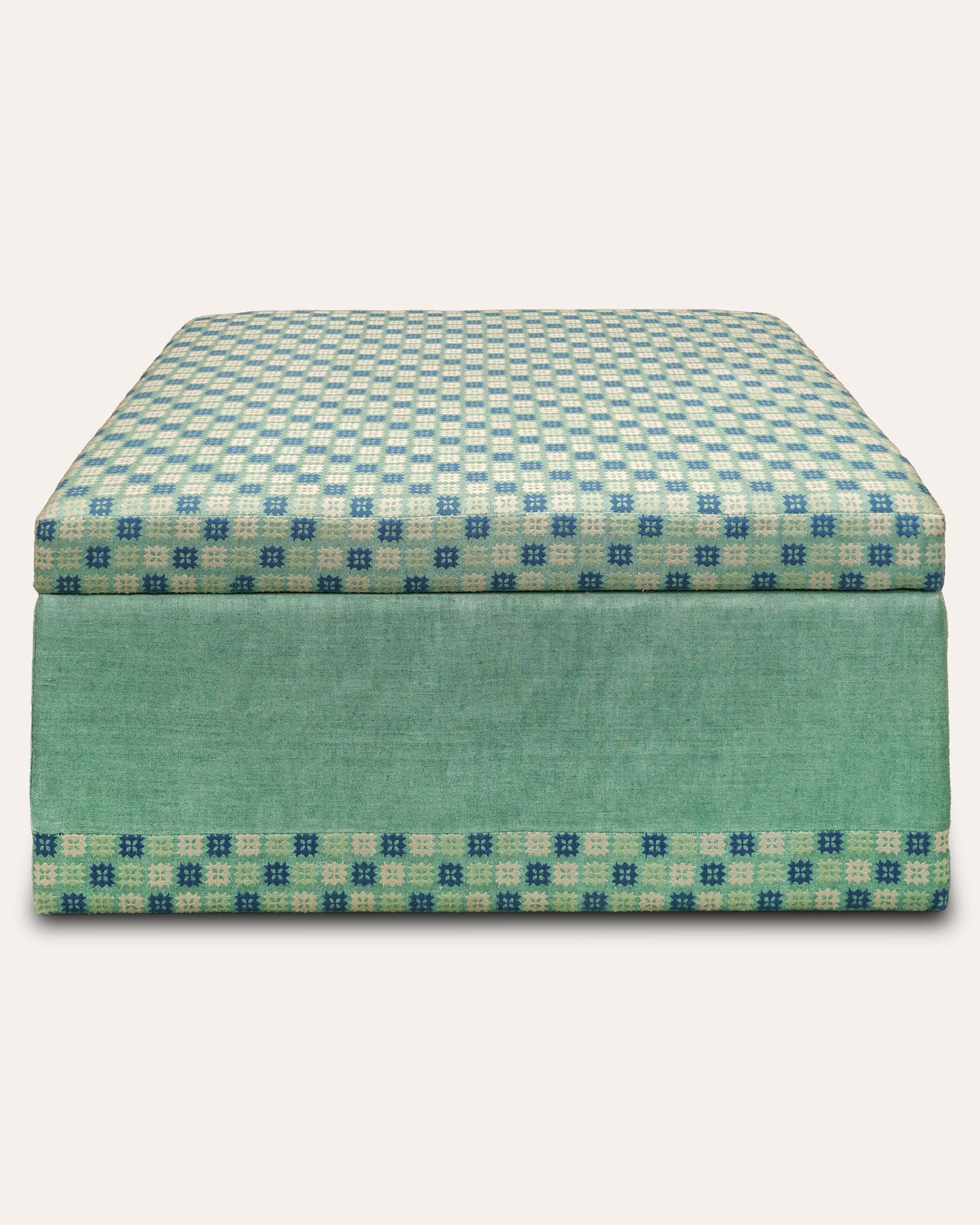 A square upholstered ottoman or storage bench with a teal and cream checkered pattern on the top and sides, and a solid teal front panel, shown against a light beige background.