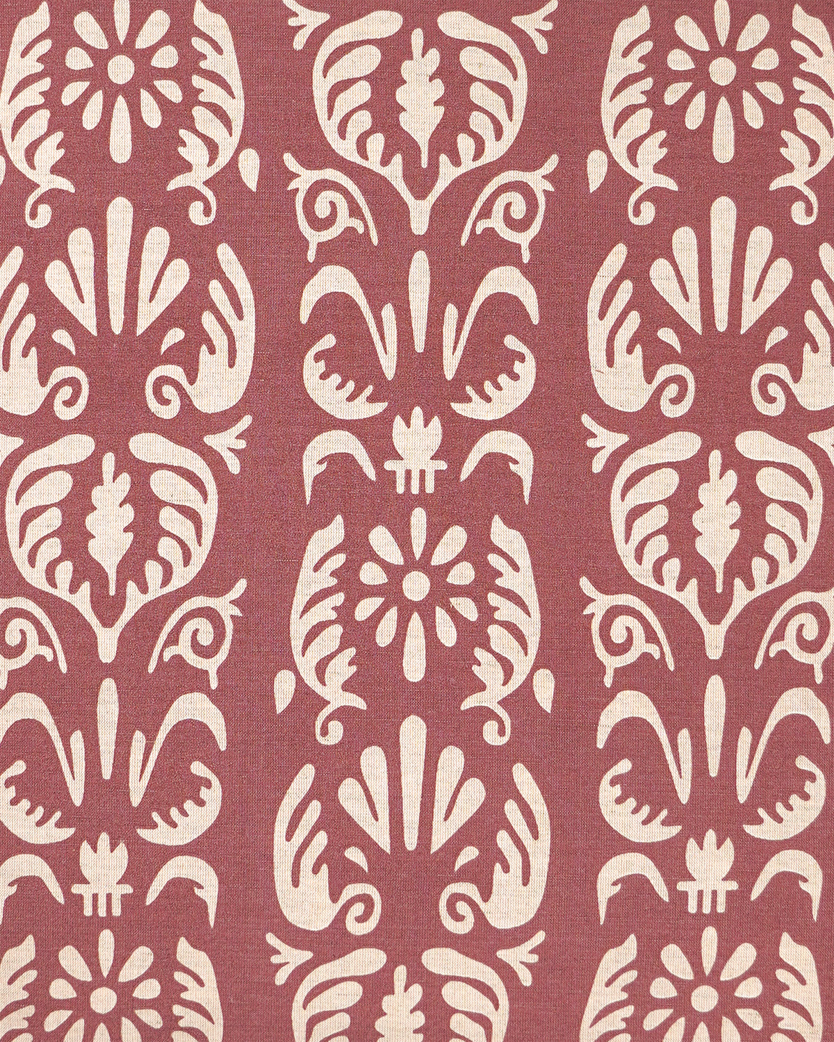 A close-up of a patterned fabric featuring a repeating vertical damask-style motif in cream on a muted dusty rose background.