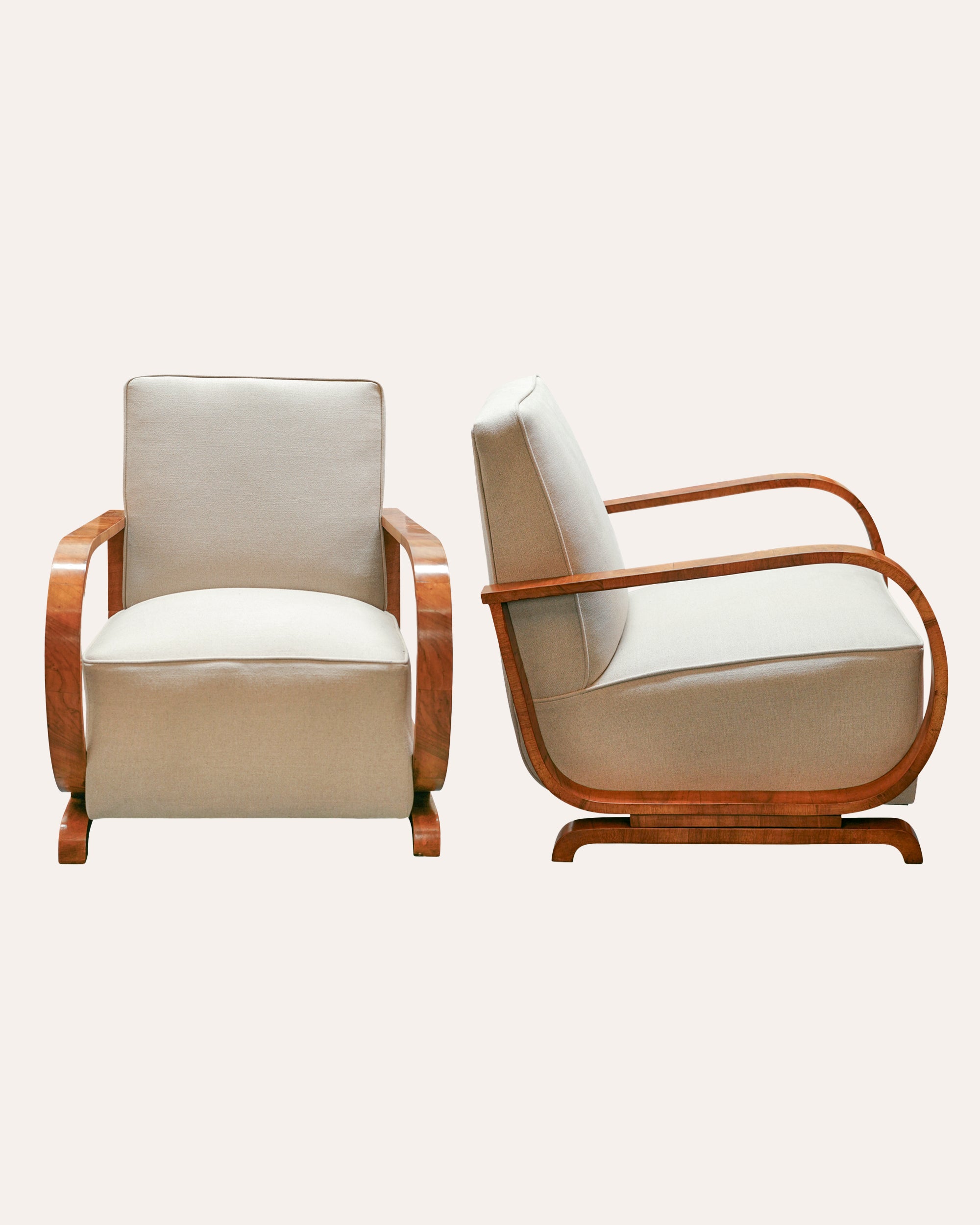 Two armchairs with white cushions and wooden frames on a light gray background