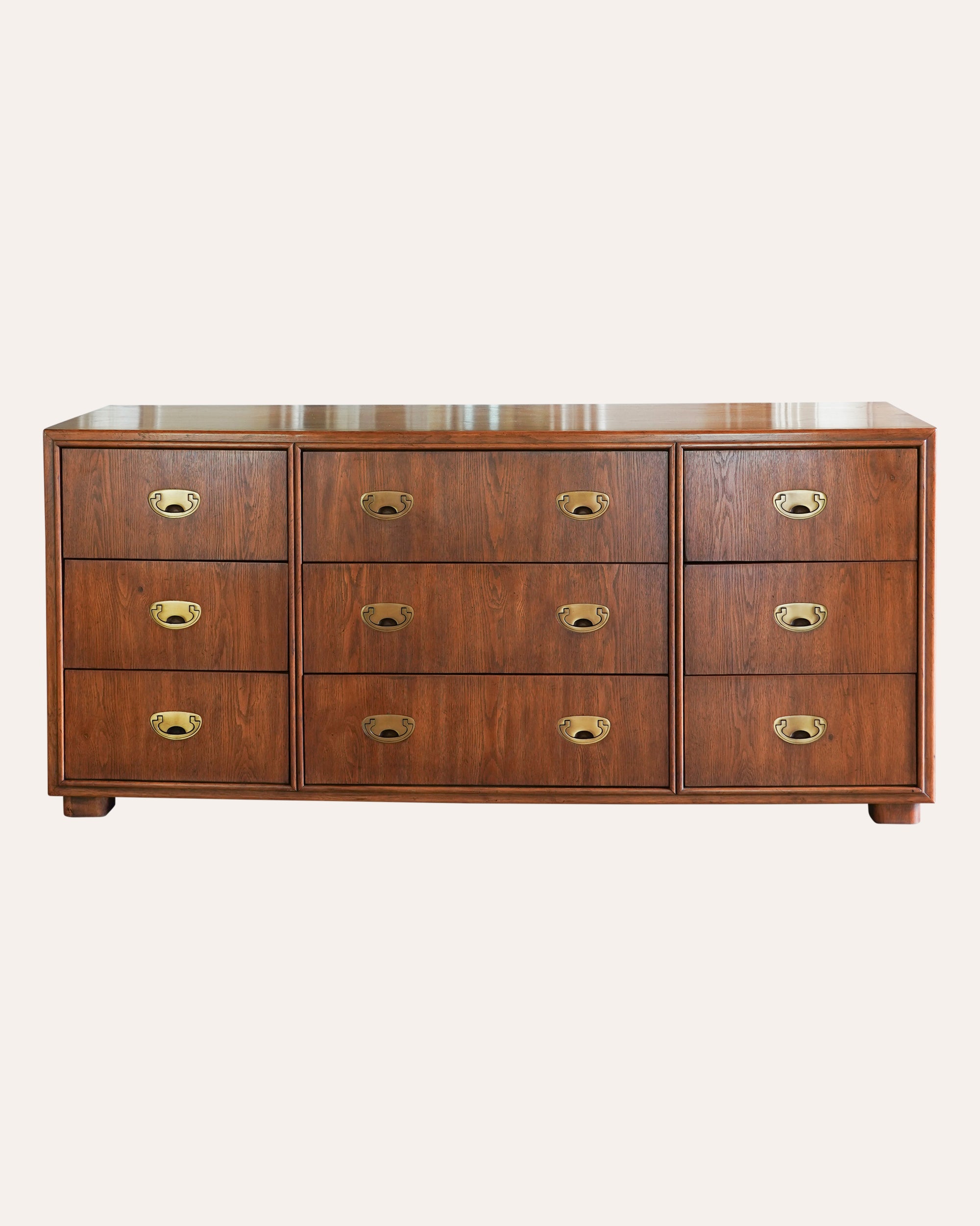 Wooden dresser with multiple drawers and brass handles on a white background