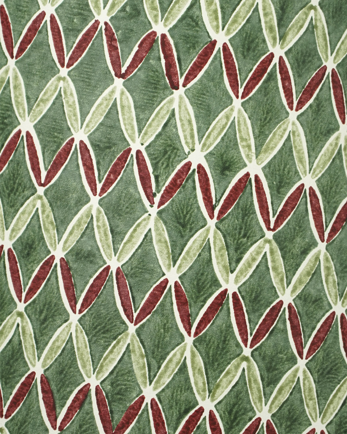 A close-up of a patterned lampshade featuring a repeating geometric design of interlocking leaf-like shapes in olive green, cream, and deep red on a muted sage green background.