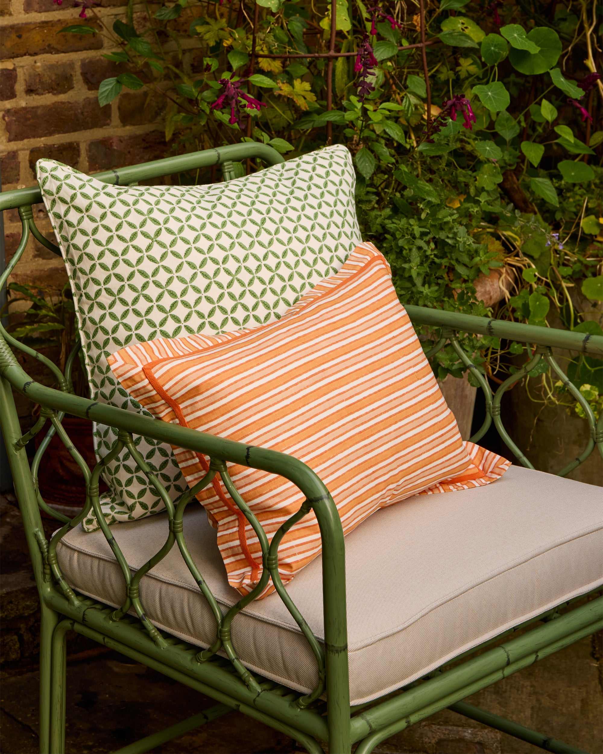 Summer outdoor seating featuring the green Curato chair styled with the orange and pink sunset striped cushion