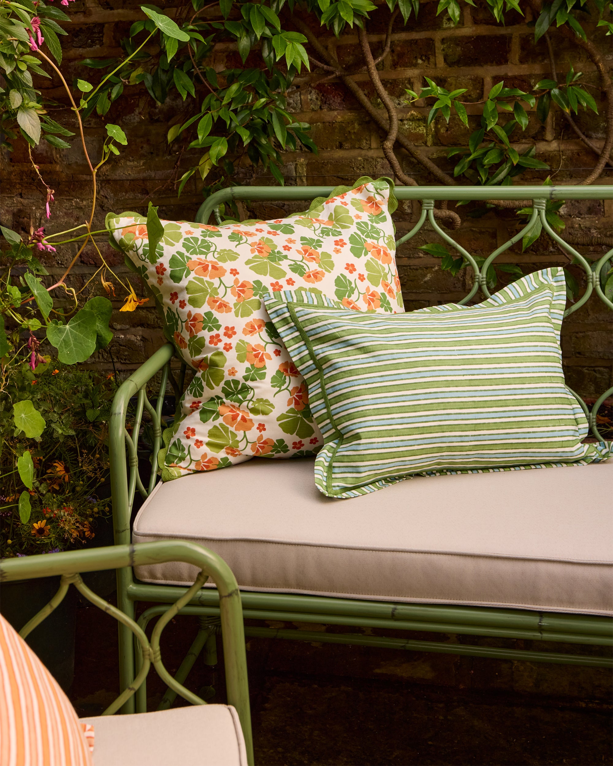 Summer lifestyle image showcasing the Nasturtium cushion, blue and green striped cushion on the Curato sofa