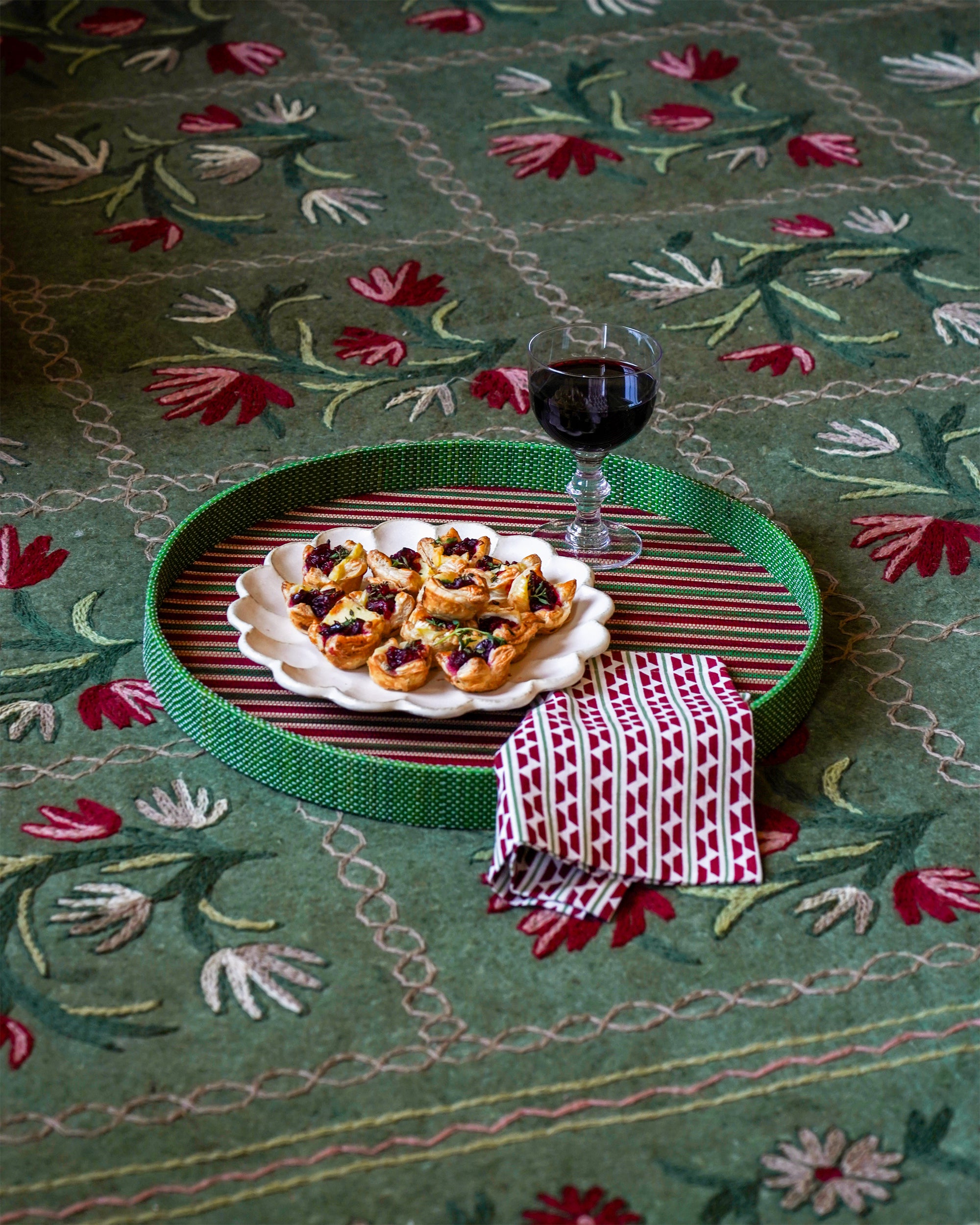 Dessert plate with pastries and a glass of red wine on a red and green striped Mendong tray