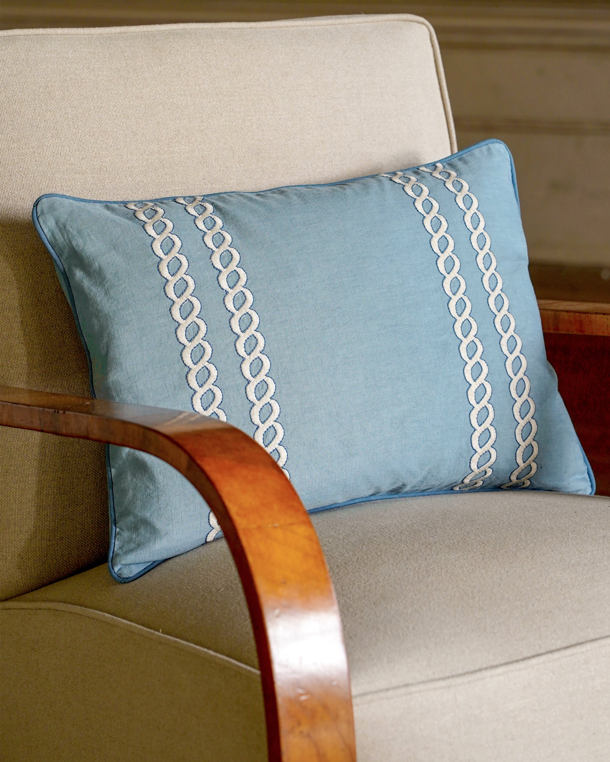 Blue pillow with white embroidery on a beige armchair