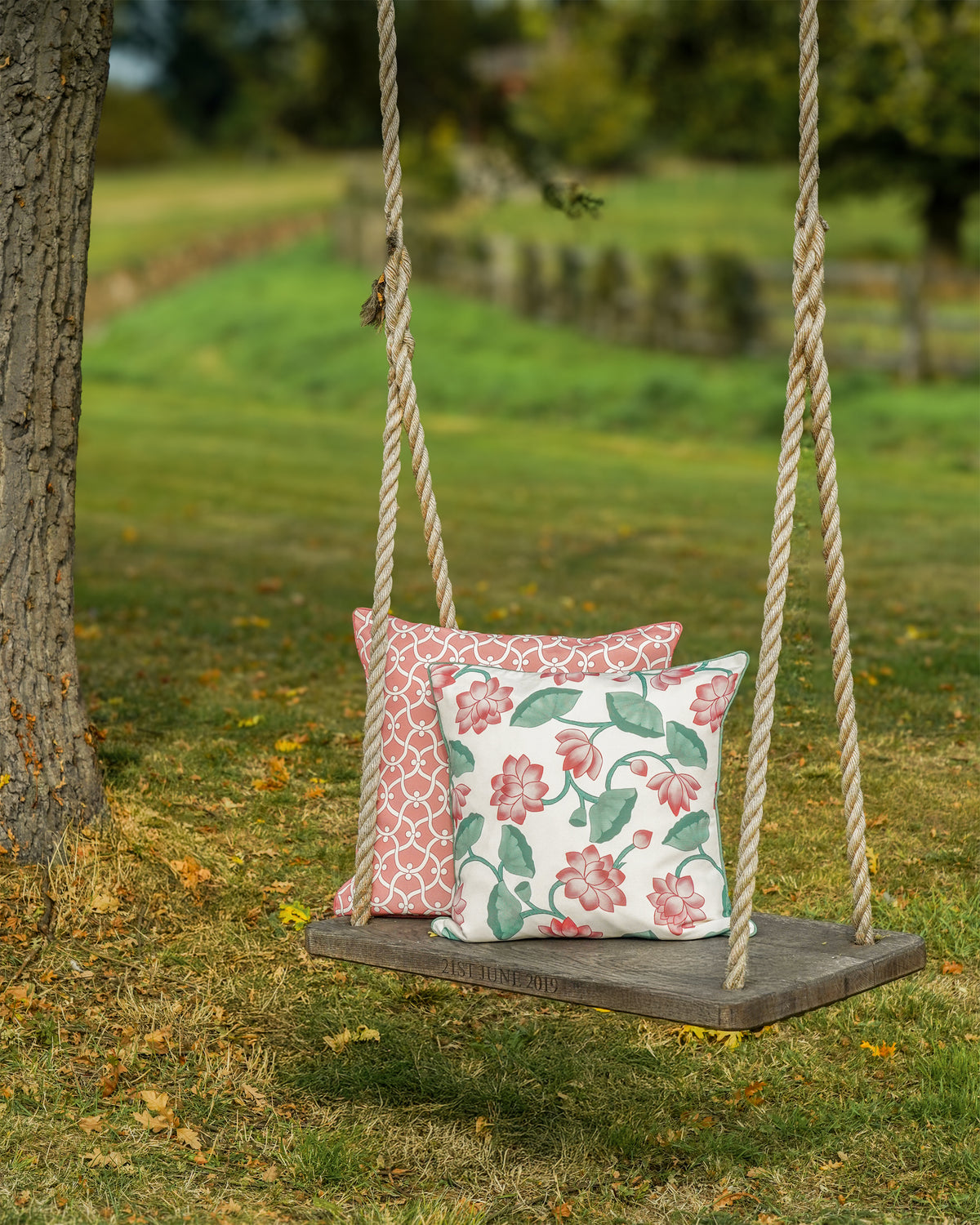 Wooden swing with two decorative cushions in a garden setting