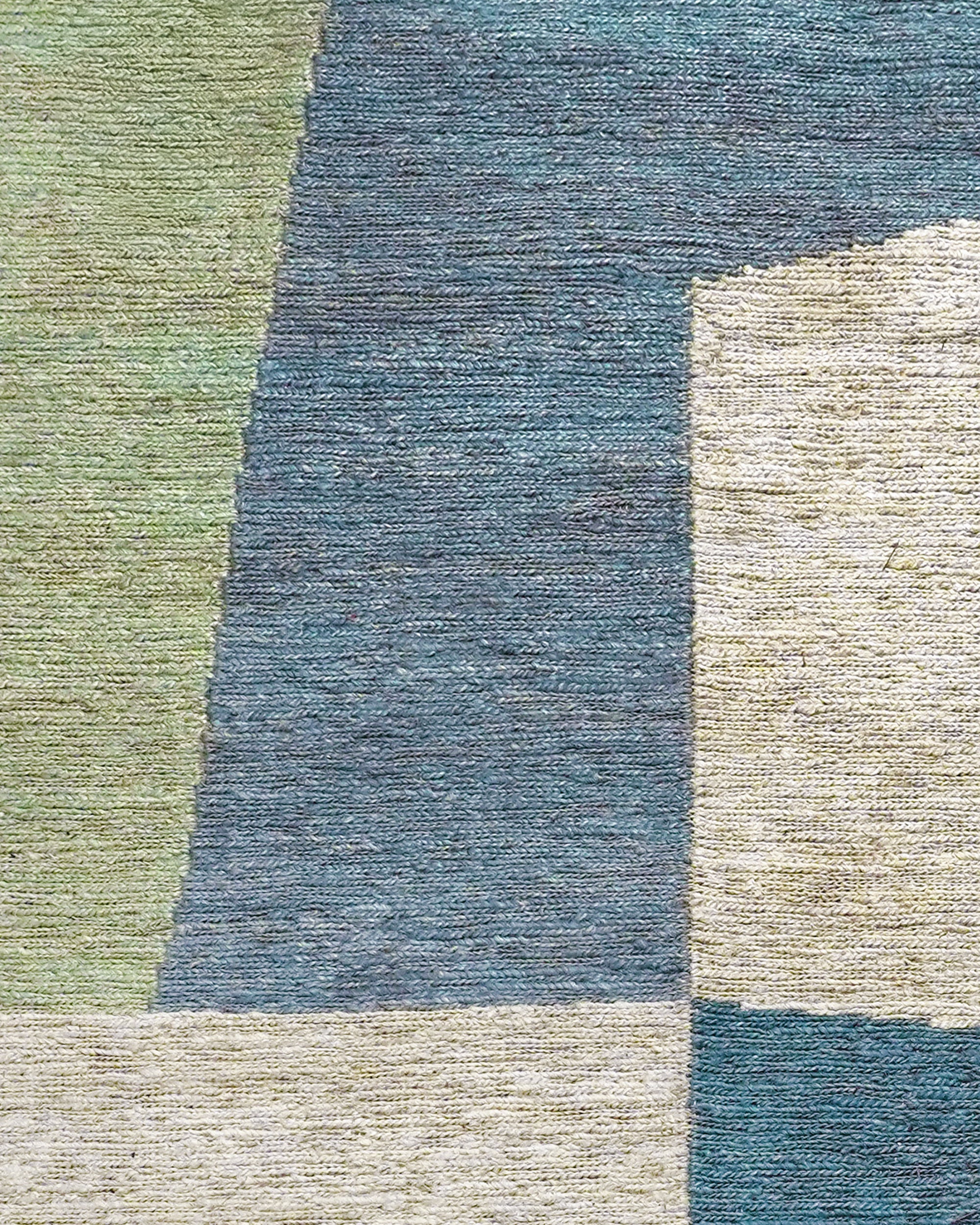 Close up detail of the abstract blue, green and taupe pattern on the Nirakar rectangular rug