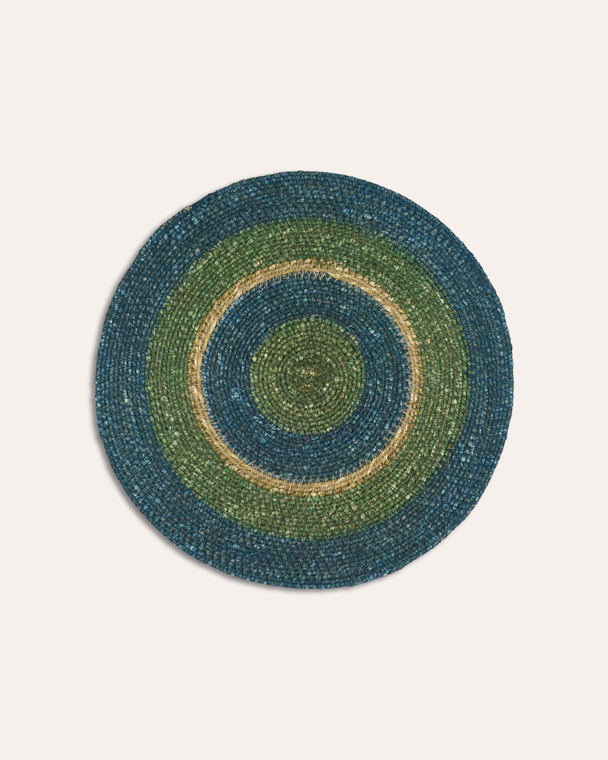 Round braided rug with concentric circles in green and blue on a light gray background