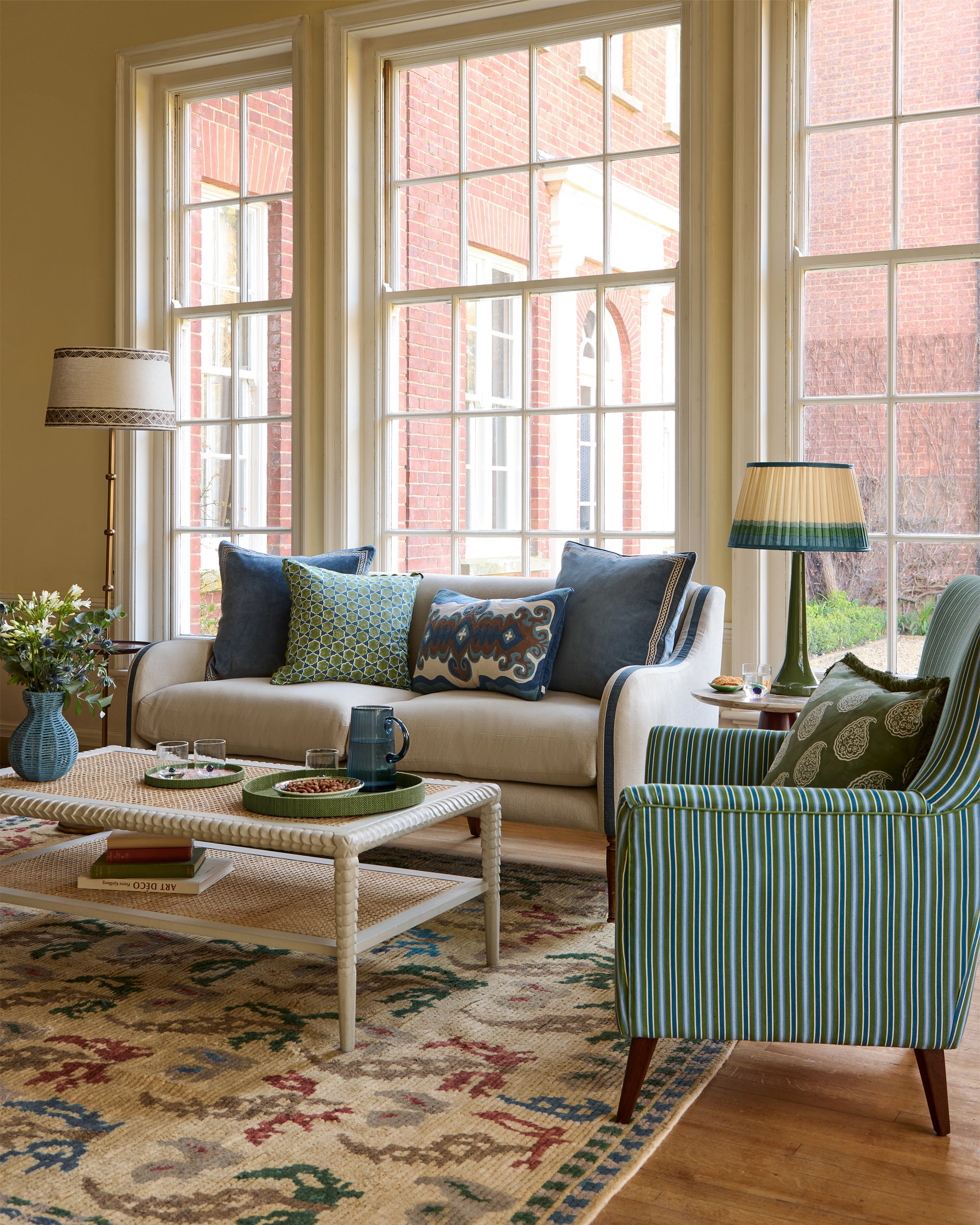 Living room with a sofa, armchair, coffee table, and large windows.