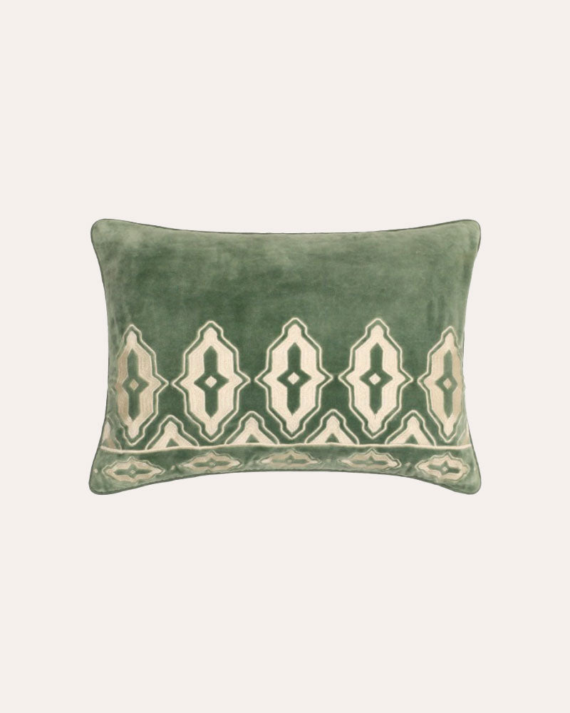 Green pillow with decorative pattern on a light beige background