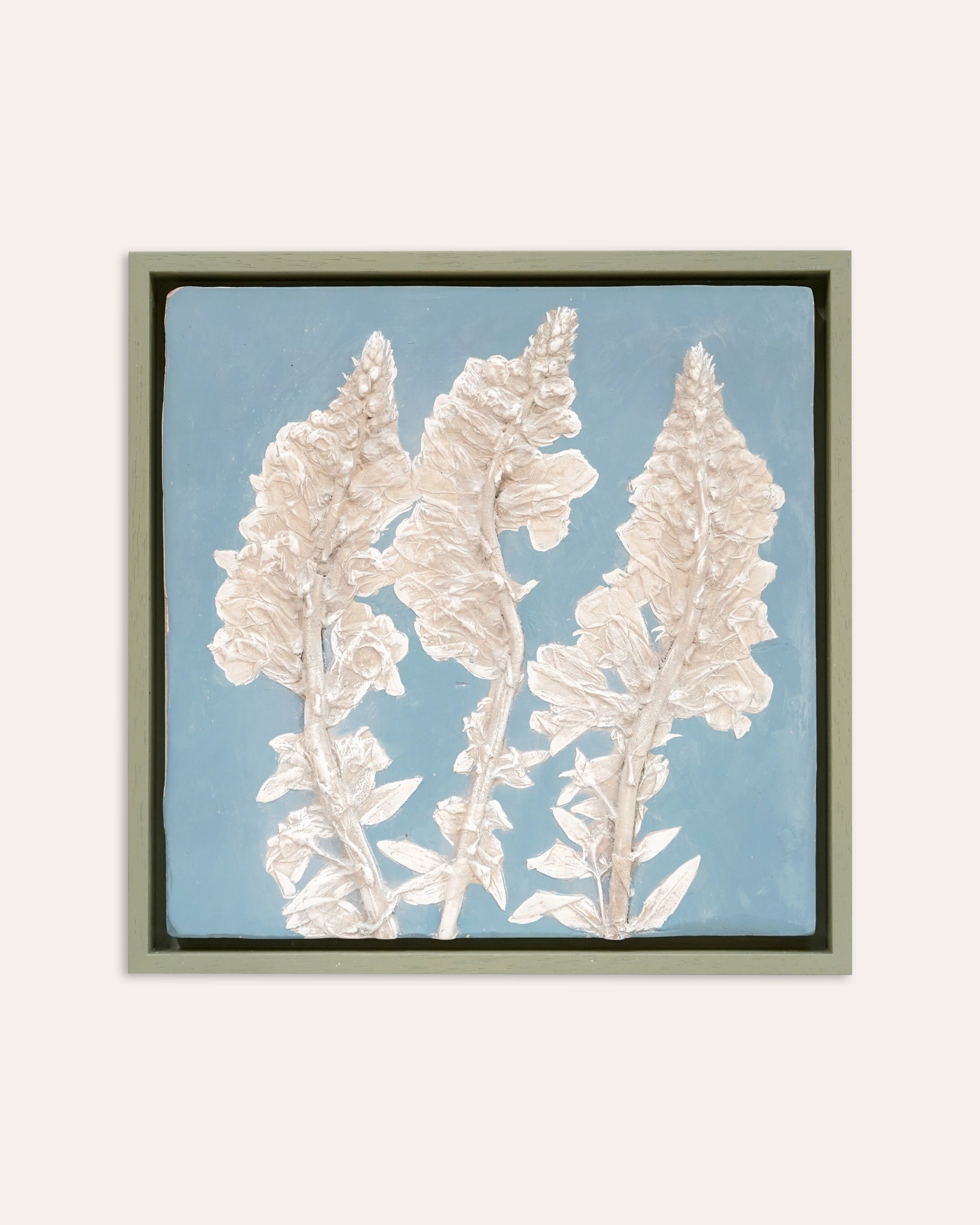 Framed artwork of white floral design on a light blue background