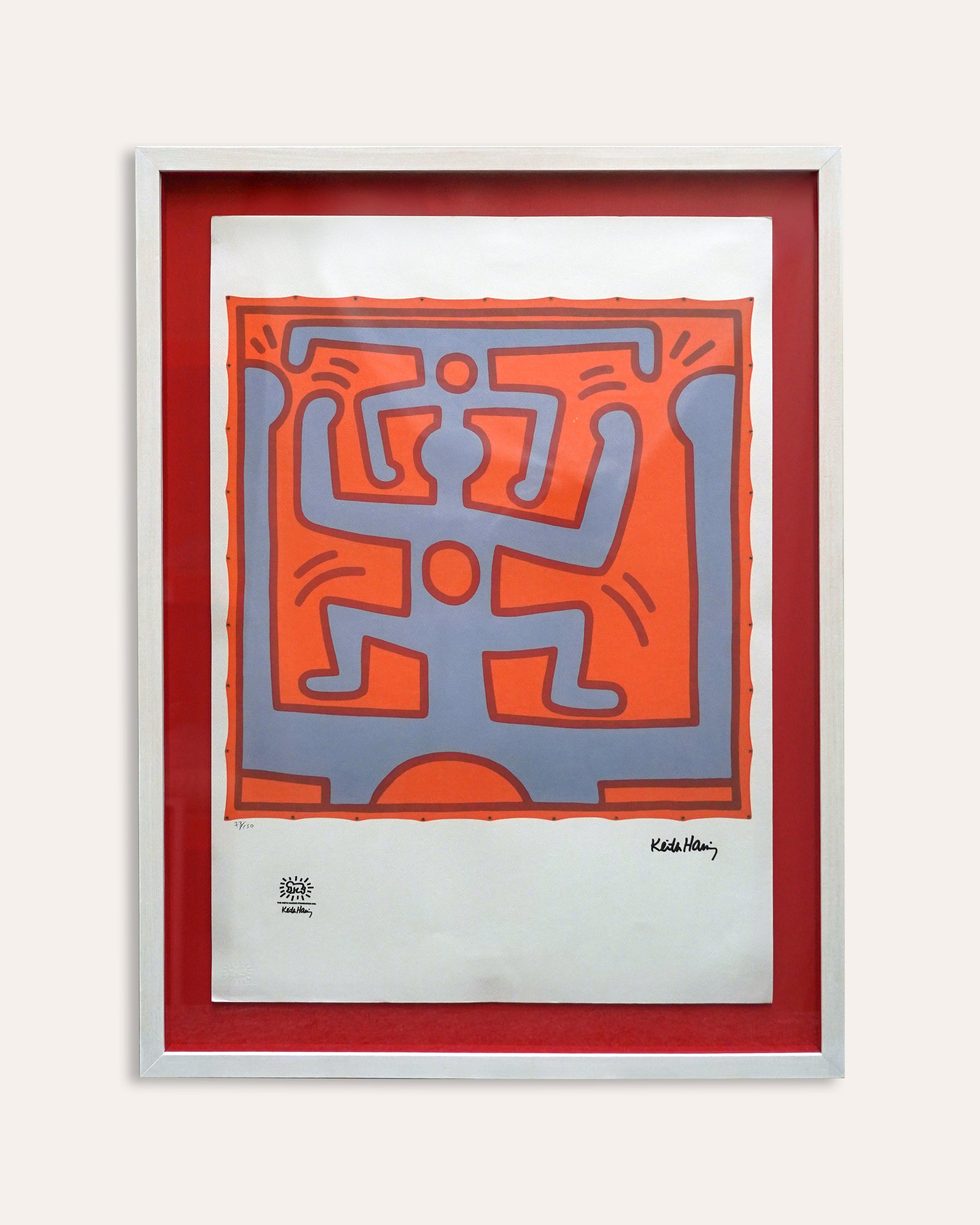 Framed artwork with a red border featuring a stylized figure design, signed by Keith Haring.