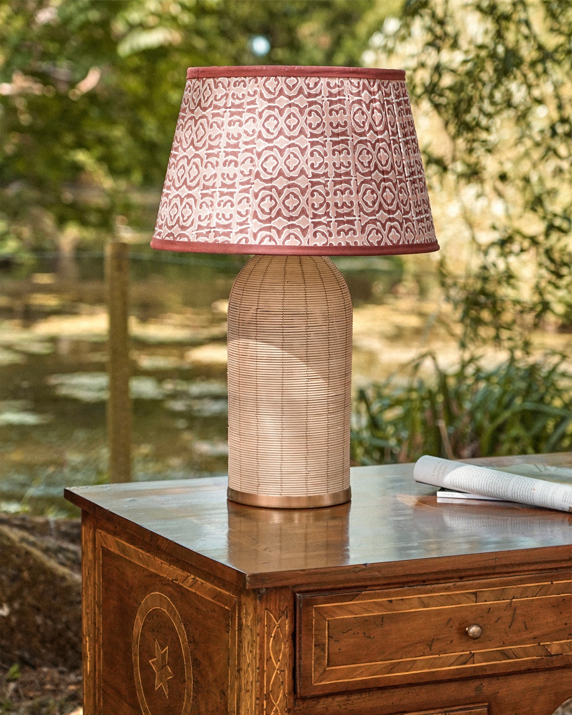 Table lamp with patterned shade on a wooden surface outdoors