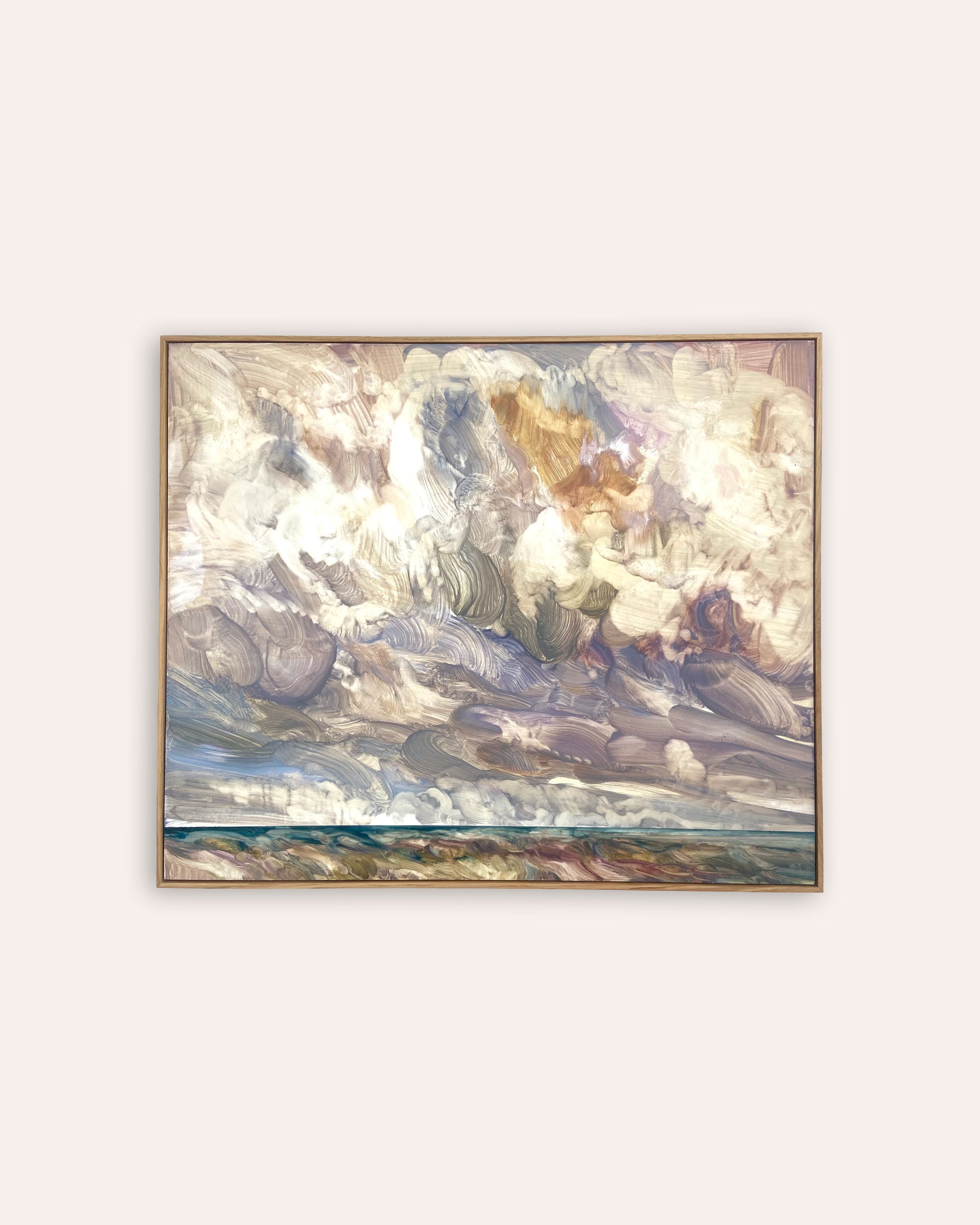 A framed painting depicting a dramatic cloudy sky with soft blue, white, beige, and brown tones, hanging on a light beige background.