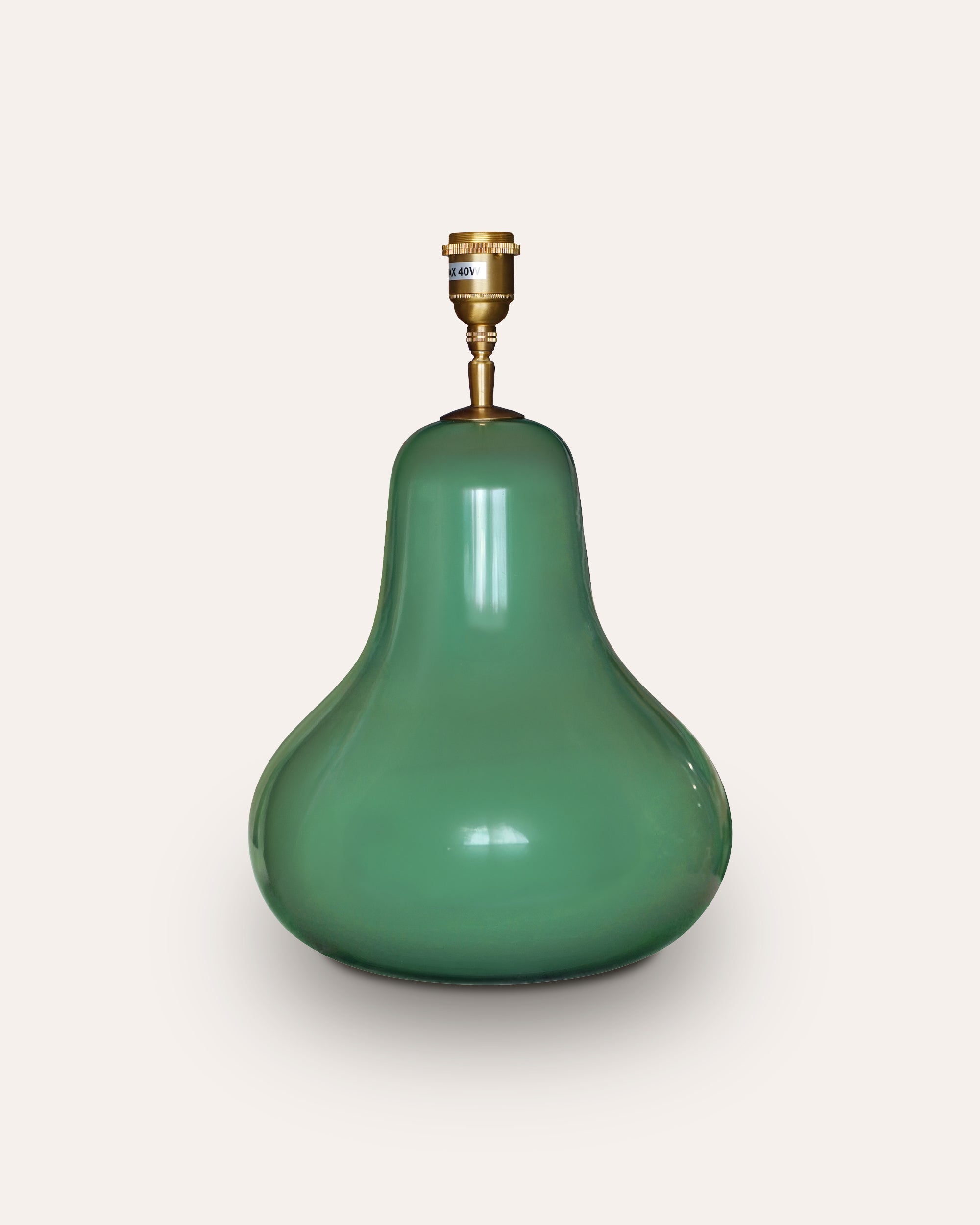 Green pear-shaped lamp with brass fitting on a light grey background