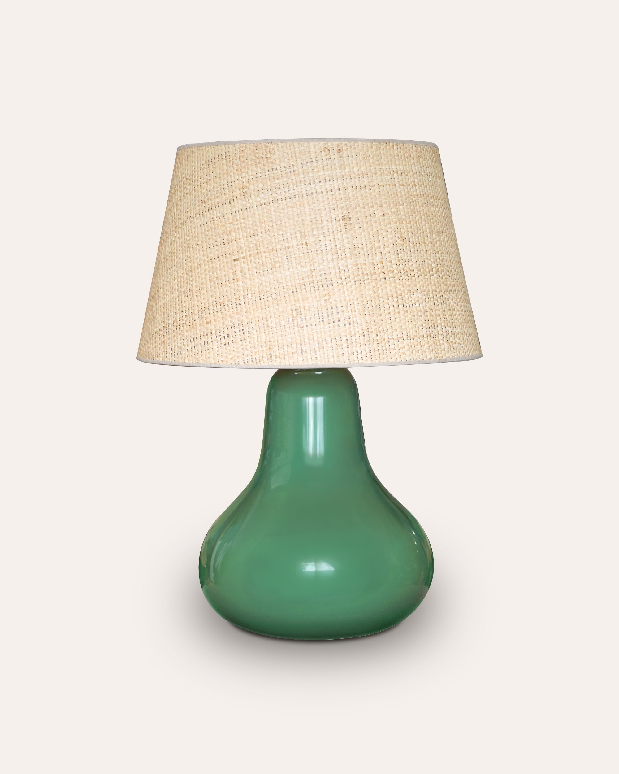 Green table lamp with a beige lampshade on a white background