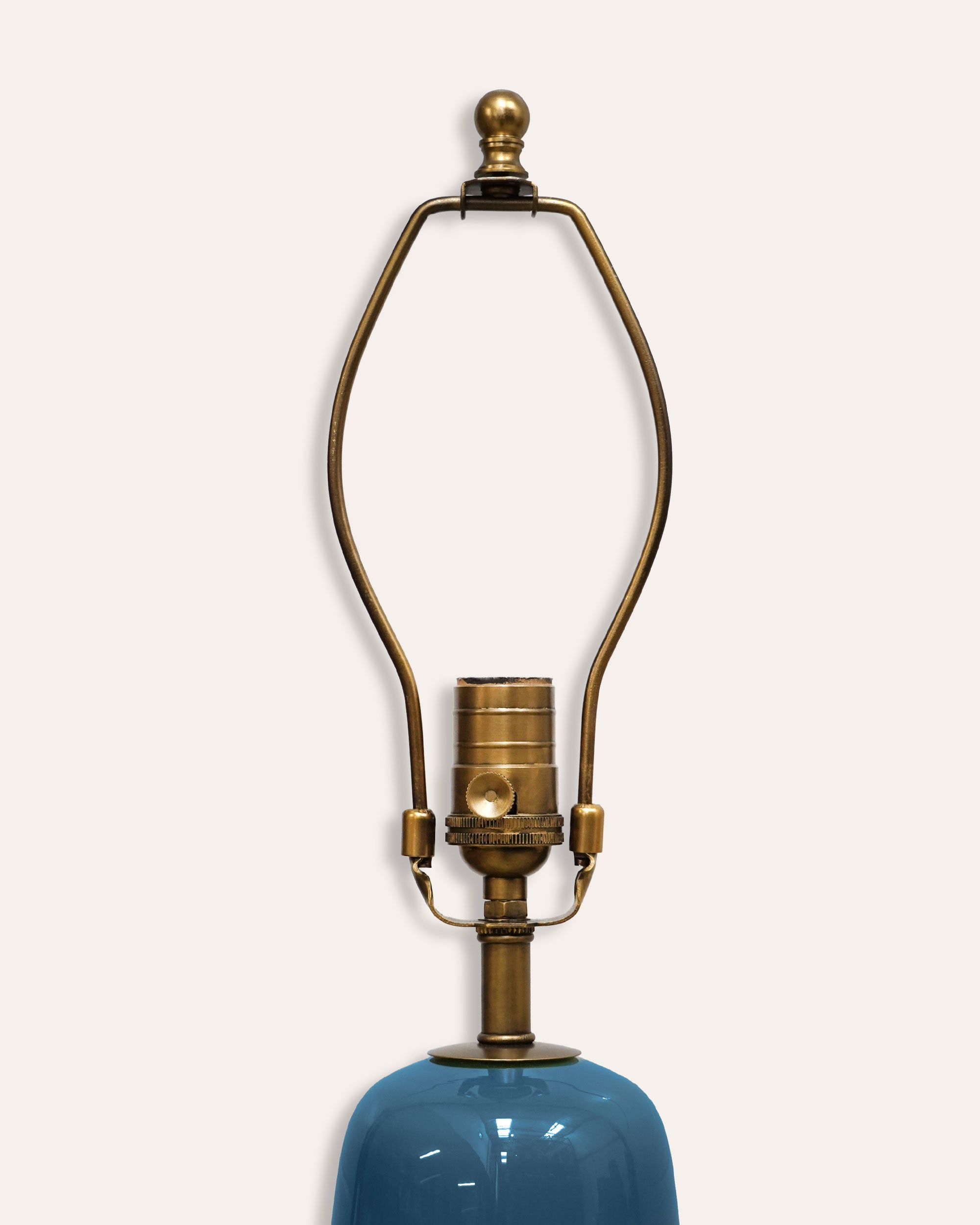 Brass lampshade on a blue ceramic base against a white background