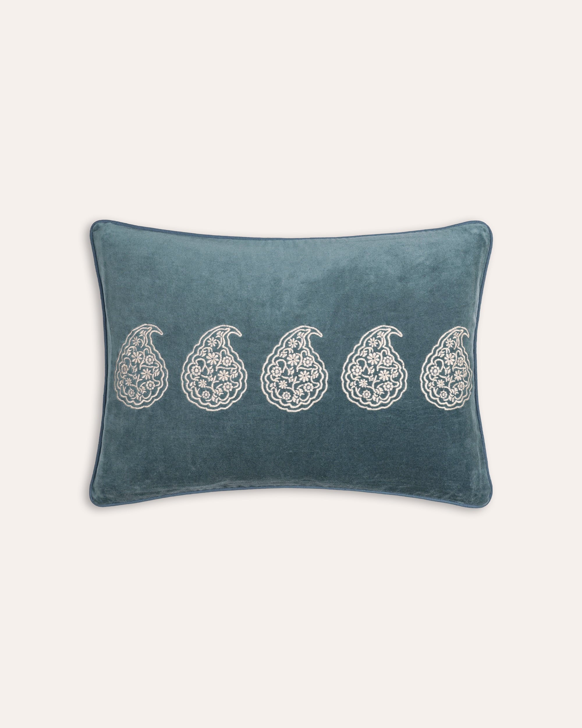 Blue cushion with white paisley patterns on a light gray background