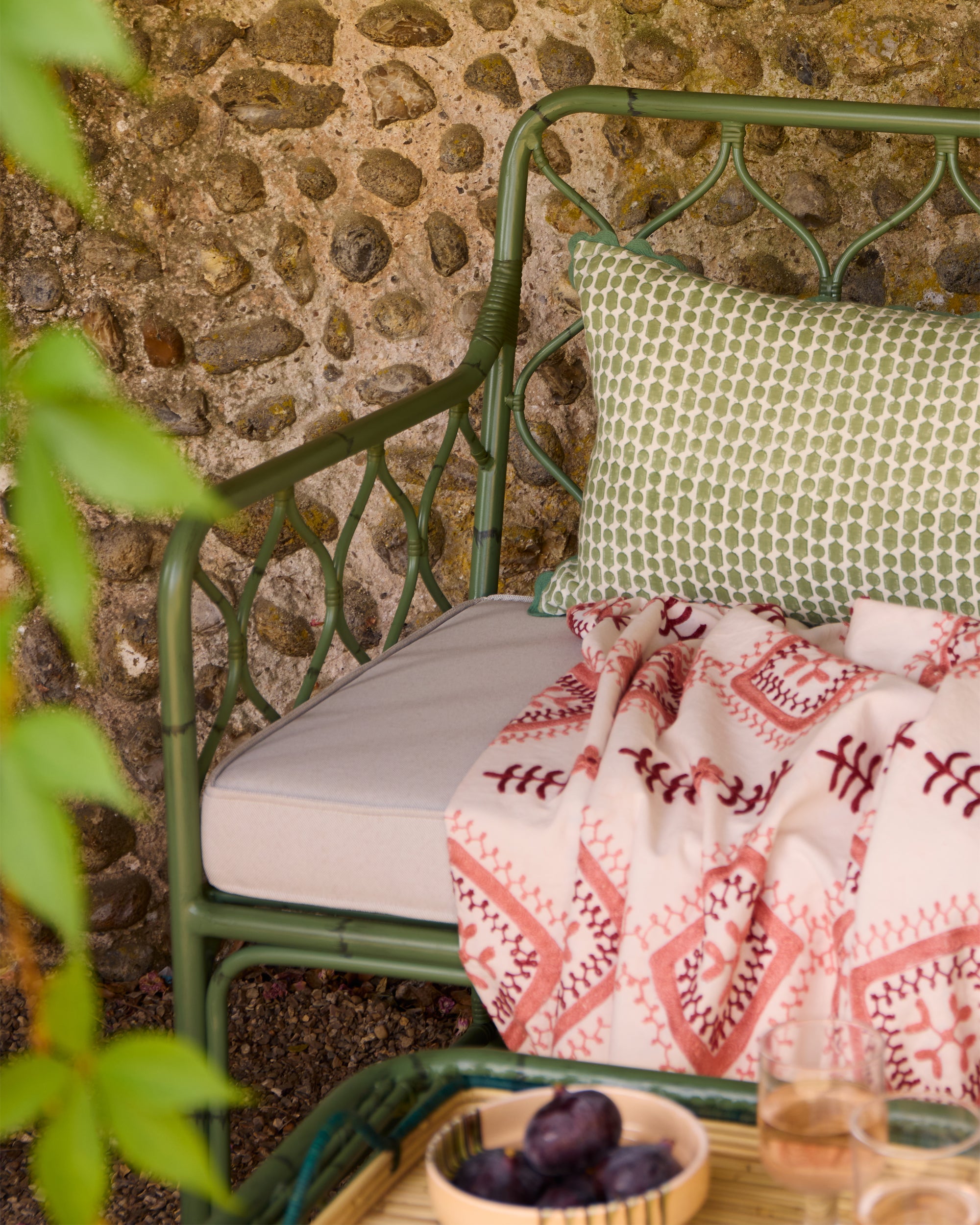 Garden image with the Curato garden sofa, Viale green cushion and pink Amrapali Suzan throw