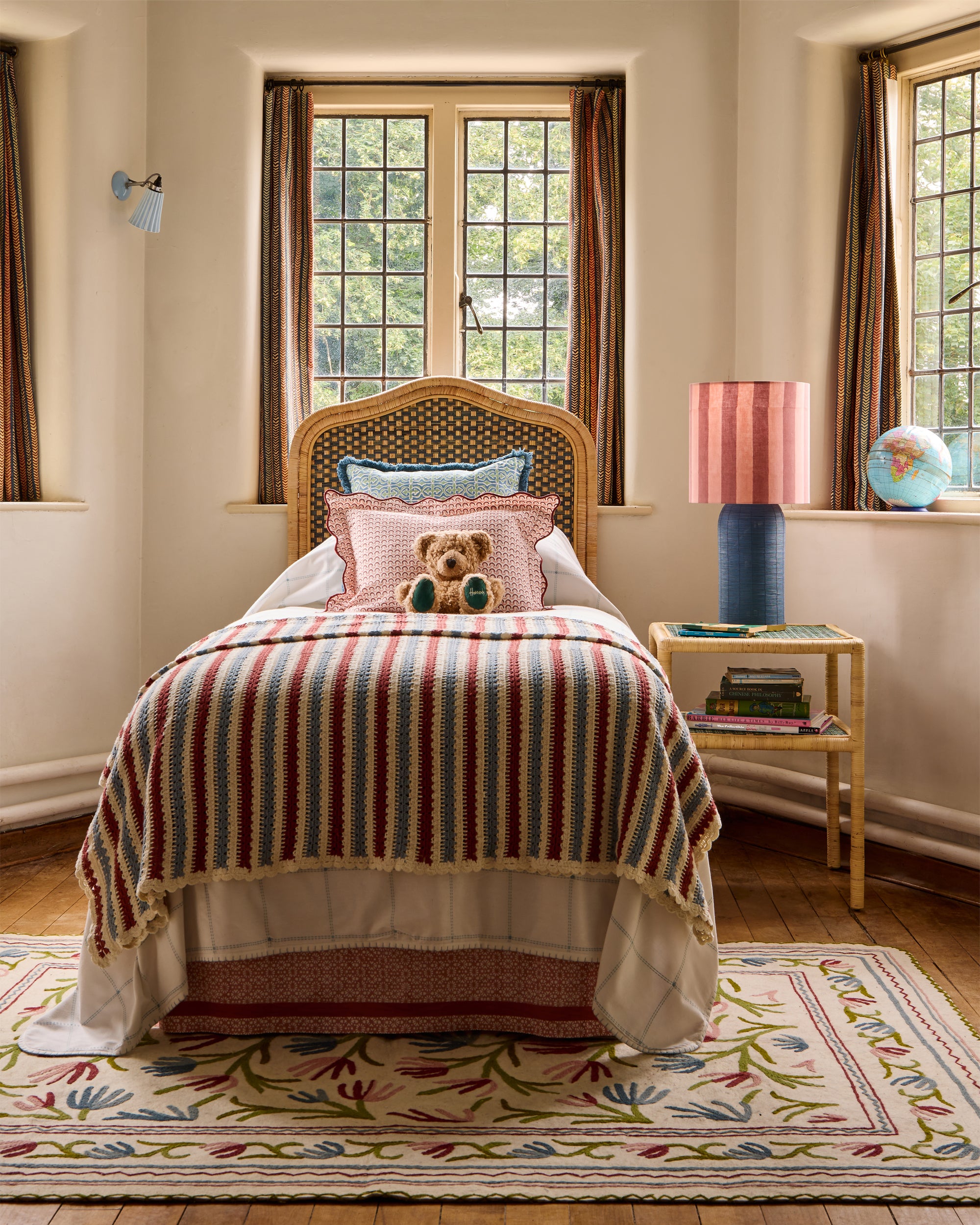 Children's bedroom featuring the blue and red striped crochet throw, blue rattan lamp with the pink and red striped drum lampshade and pink bed valence