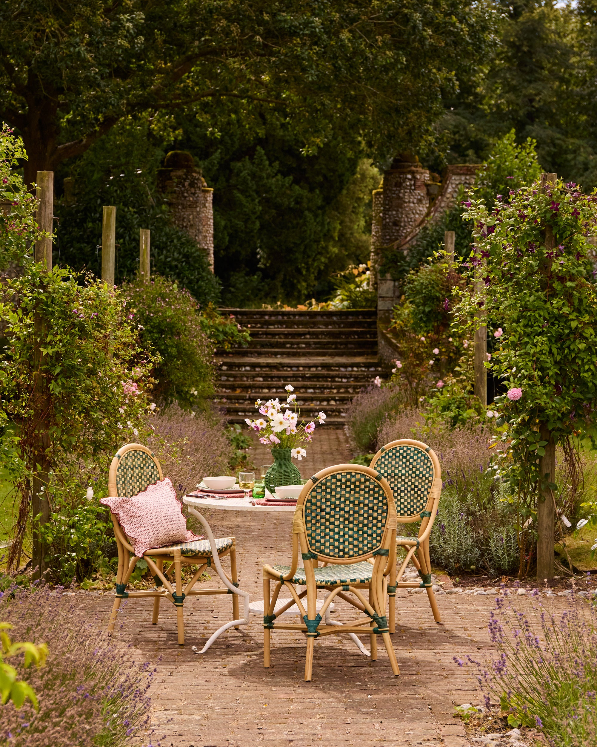 Outdoor spring summer dining, styled with the green rattan dining chairs, pink Teja scalloped cushions and Birdie Fortescue's antique white table