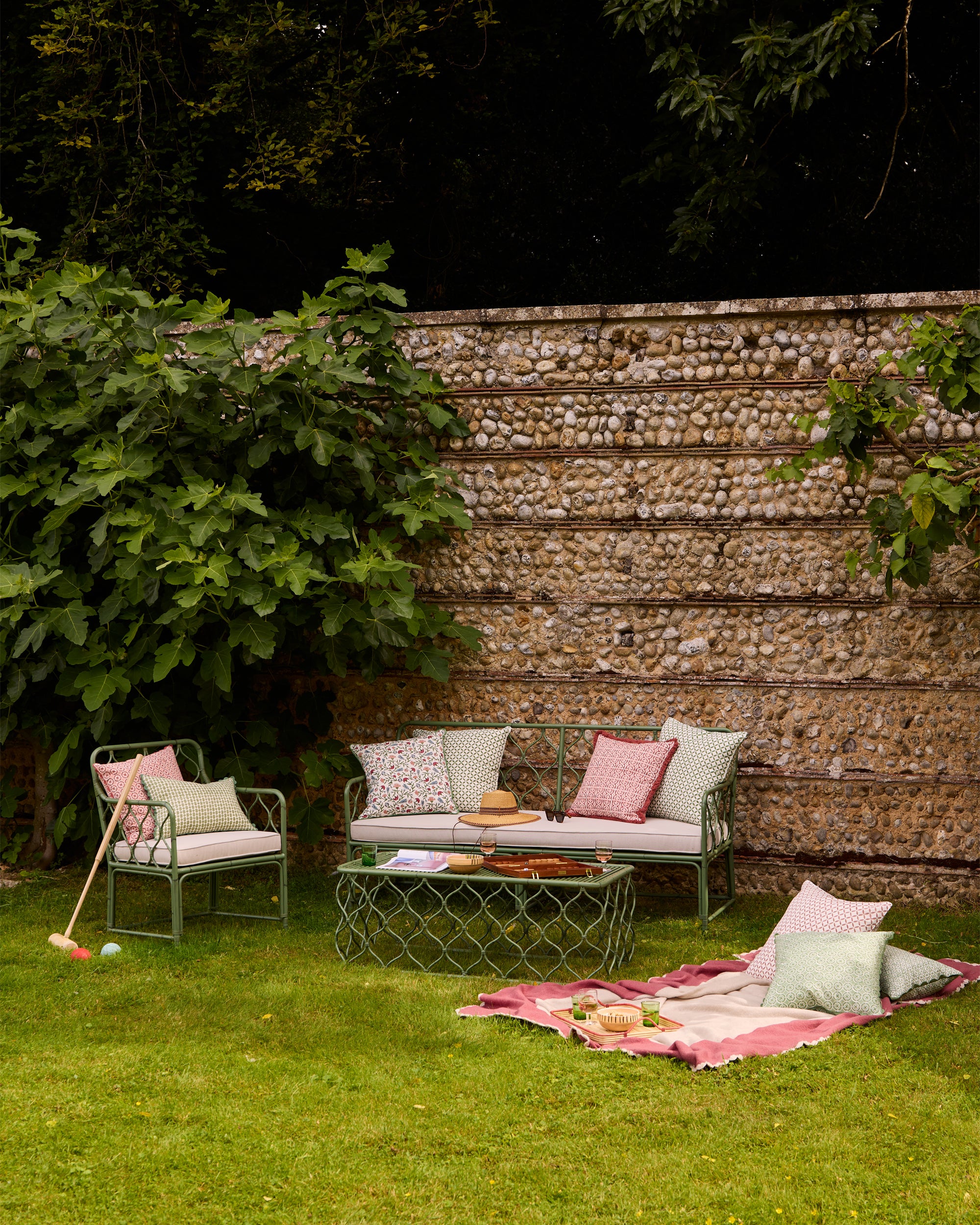 Summer outdoor garden lifestyle image, featuring pink and green soft furnishings and our Curato garden furniture set