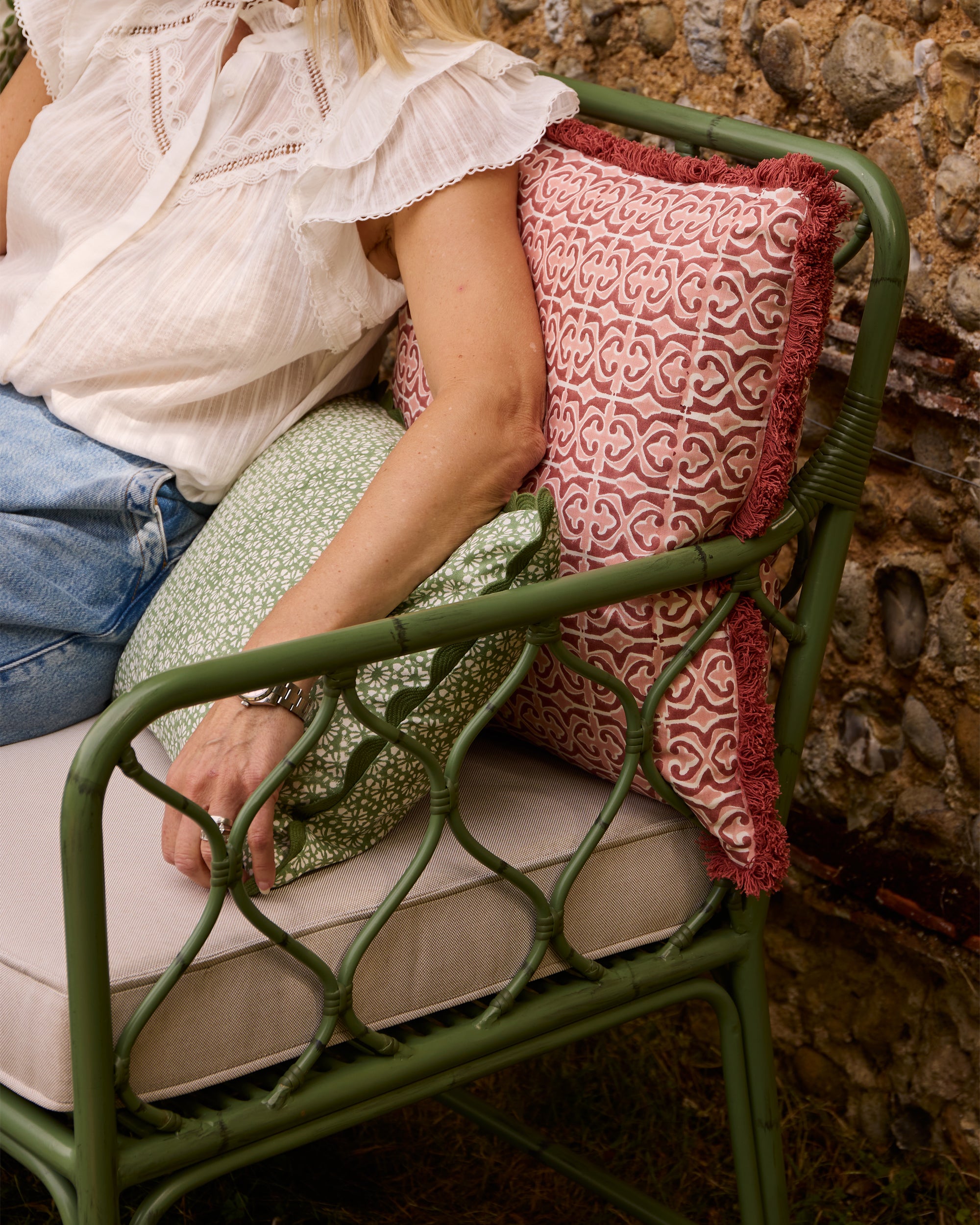 Close up lifestyle image of a person relaxing on Birdie Fortescue's curato outdoor sofa, styled with the pink Santa Clara cushion