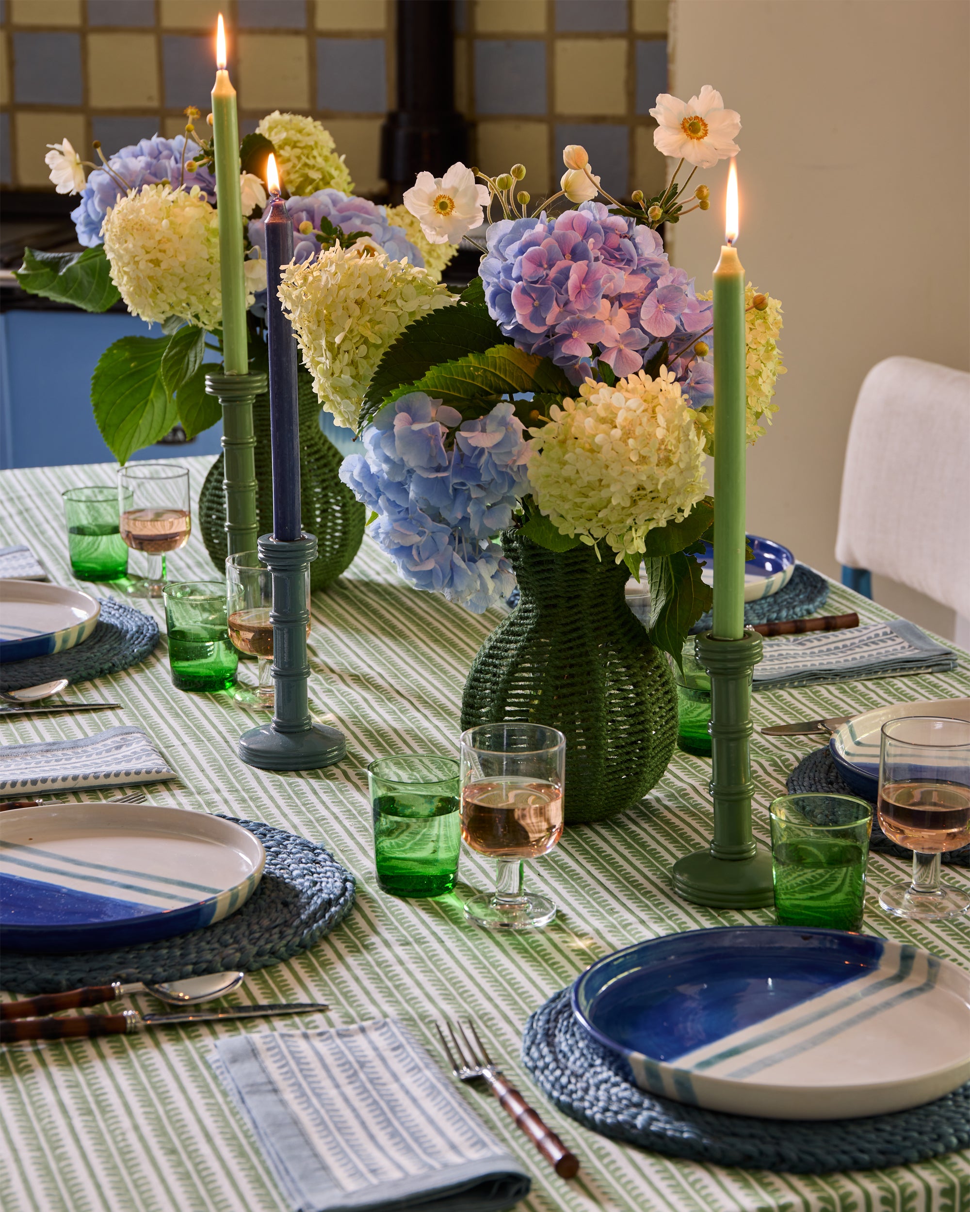 Blue and green close up spring summer dining image, focusing on the green string vases and column candlesticks as centre pieces