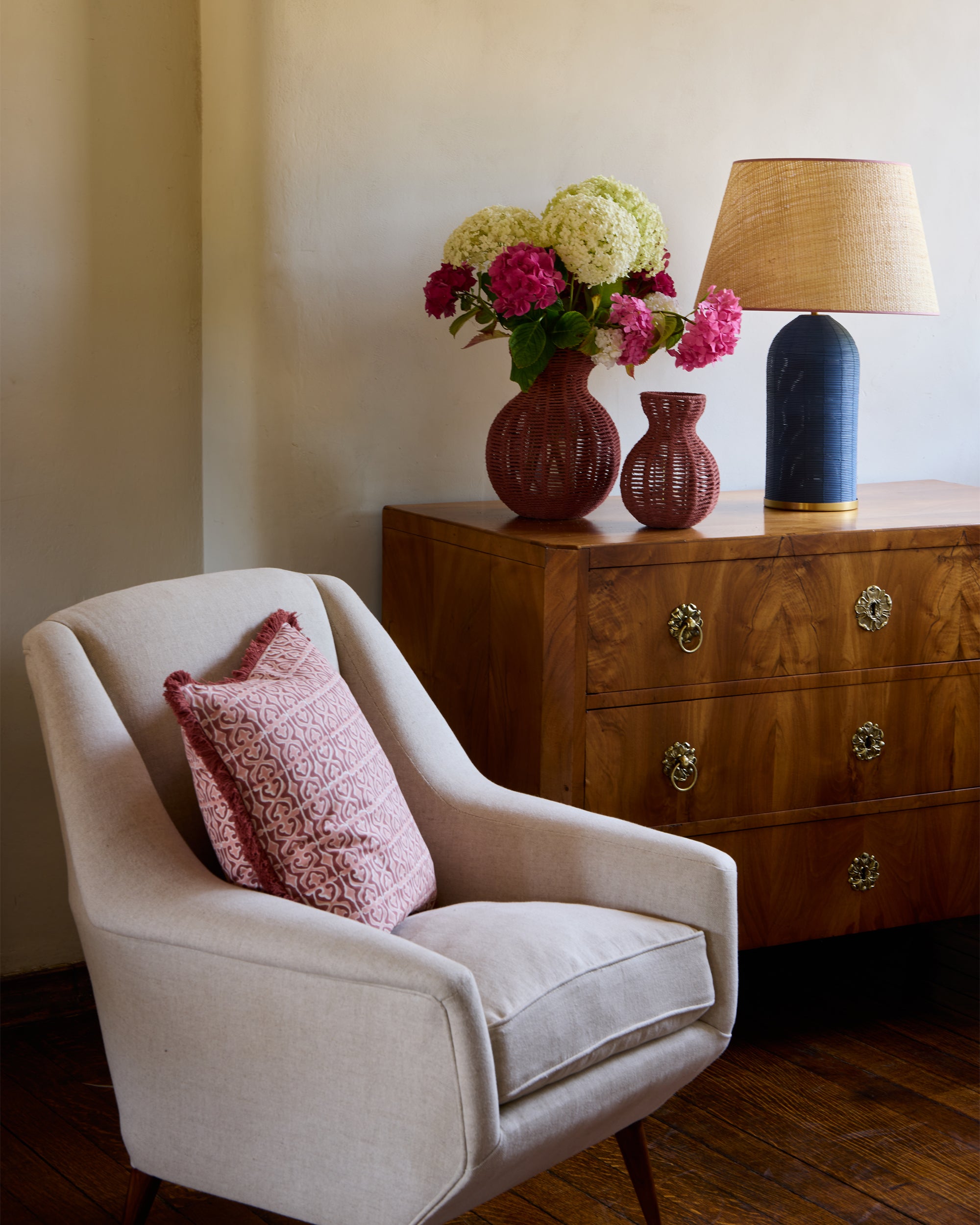 Blue and pink armchair lifestyle image, featuring our pink string vases styled on an antique Chester drawer