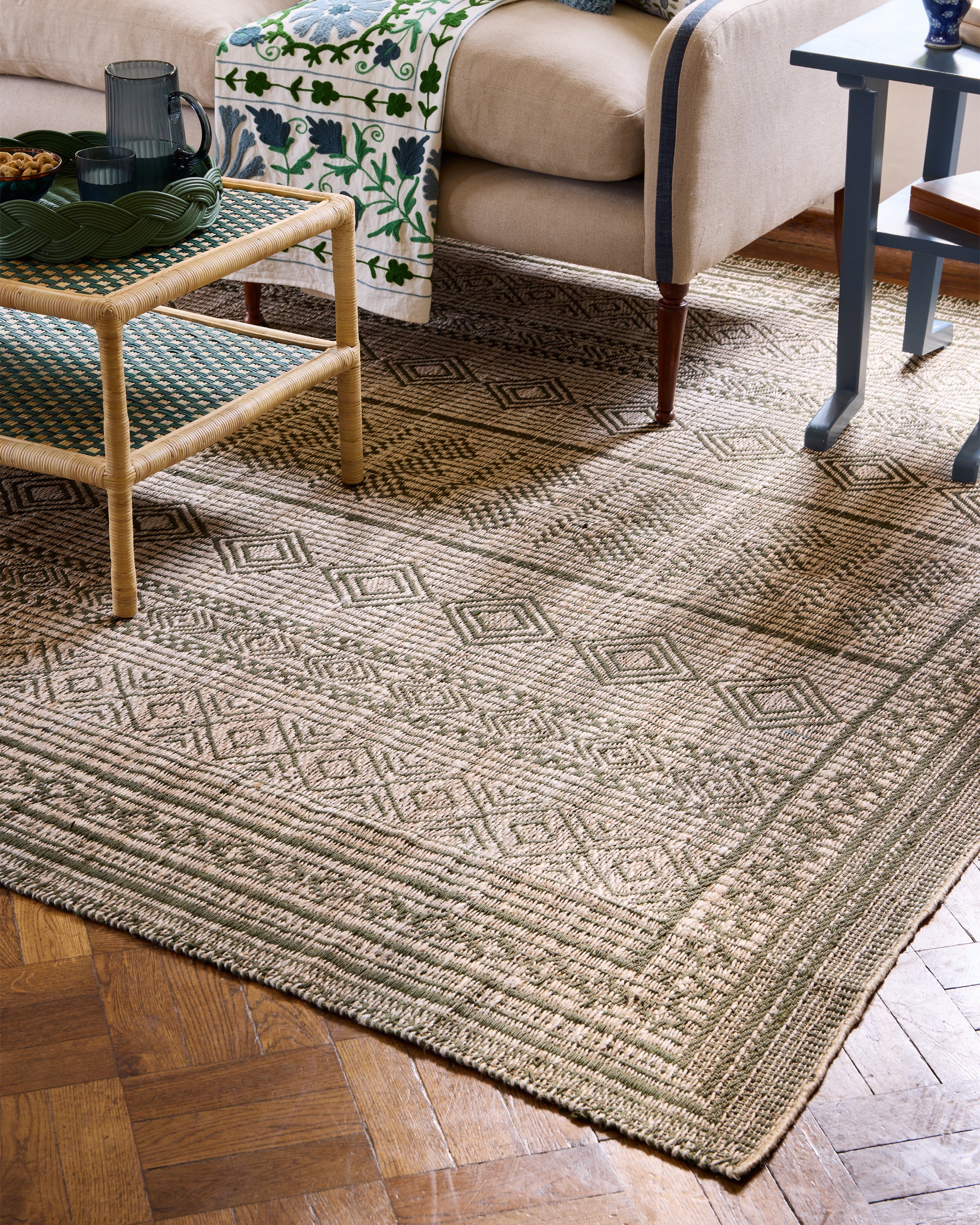 Lifestyle image showing the corner of the green moroccan jute rug in a blue and green themed sitting room