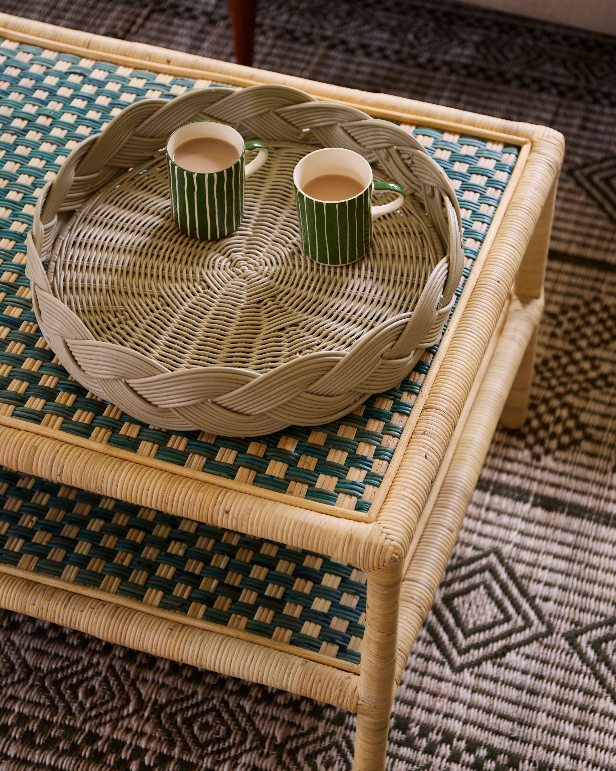 Relaxed sitting room close up, showcasing the taupe rattan circular tray on the green rattan coffee table