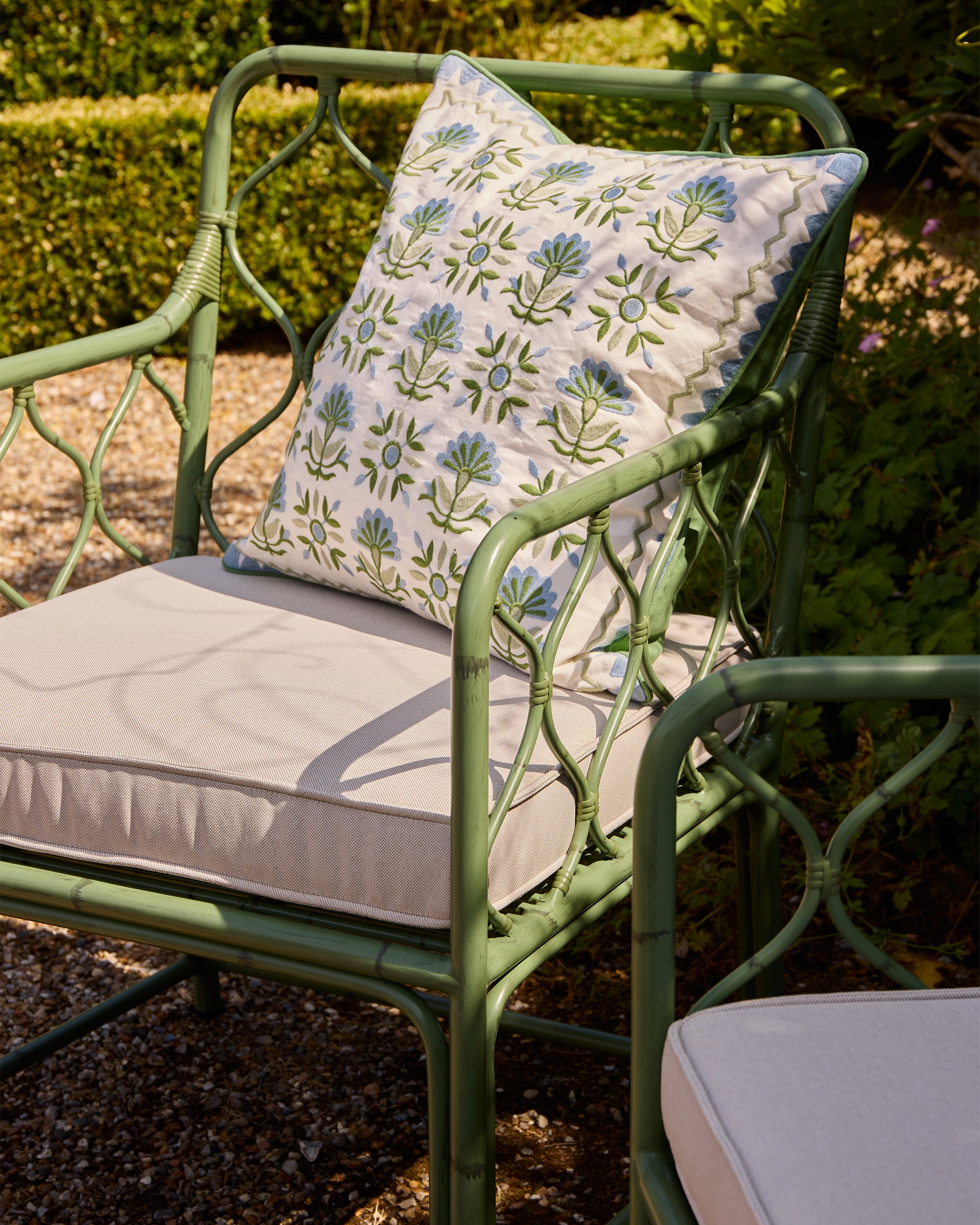 Summer garden shot showcasing the Curato Garden Chair with the Sancti Embroidered Statement Cushion