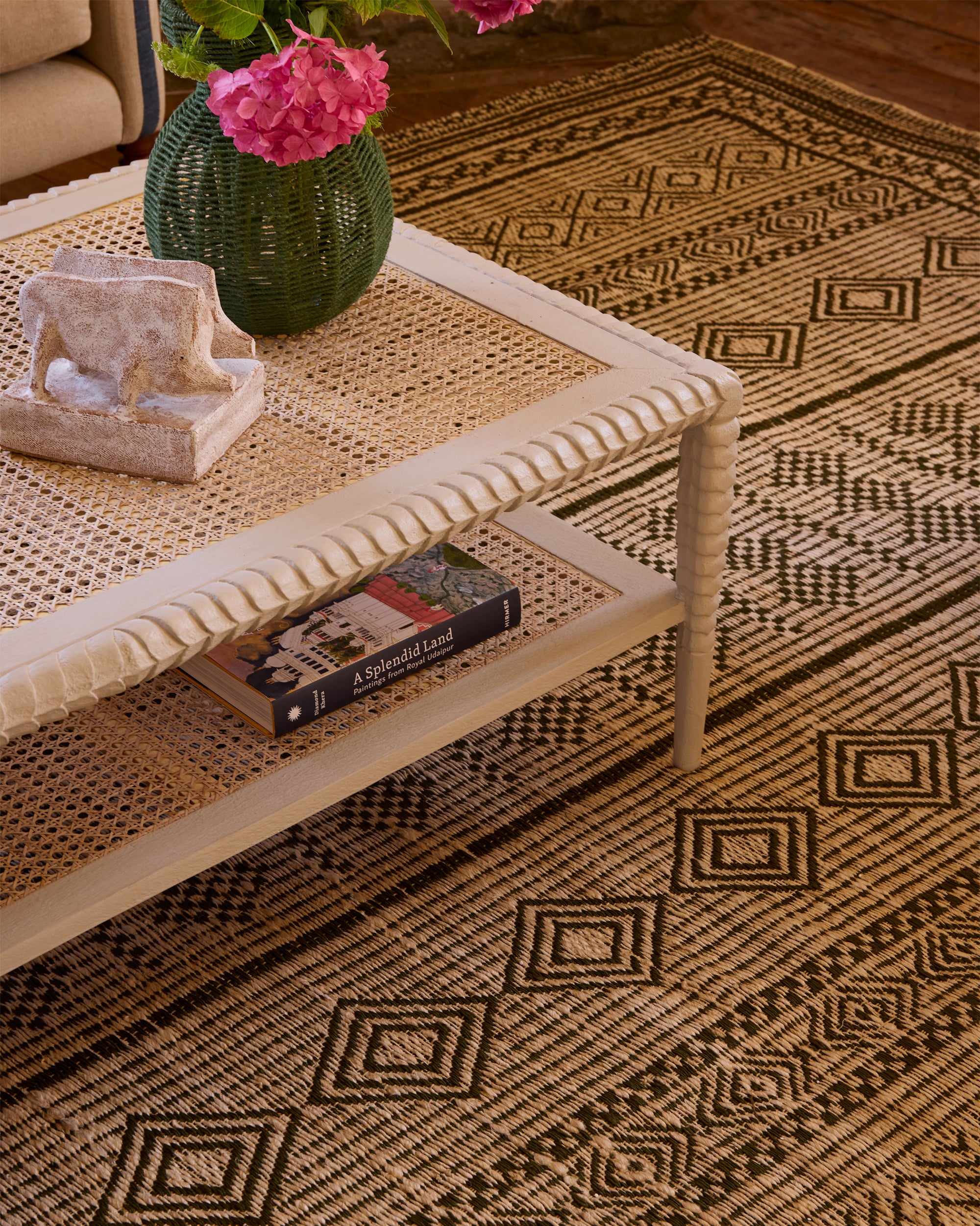 Close up detail lifestyle image showcasing the taupe pavilion ottoman and green moroccan jute rug