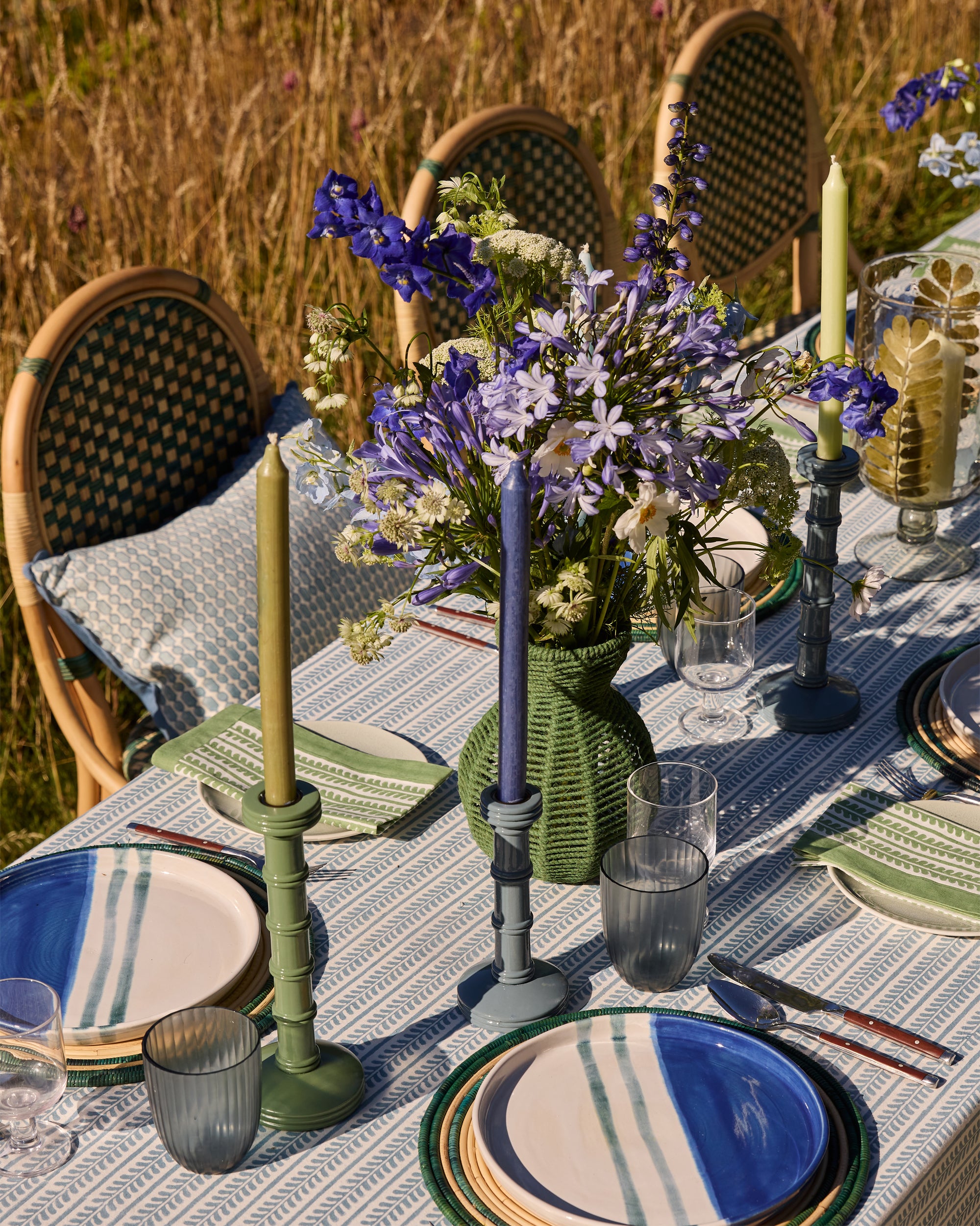 Summer outdoor dining, green string vases filled with flowers and blue and green column candlesticks as center pieces