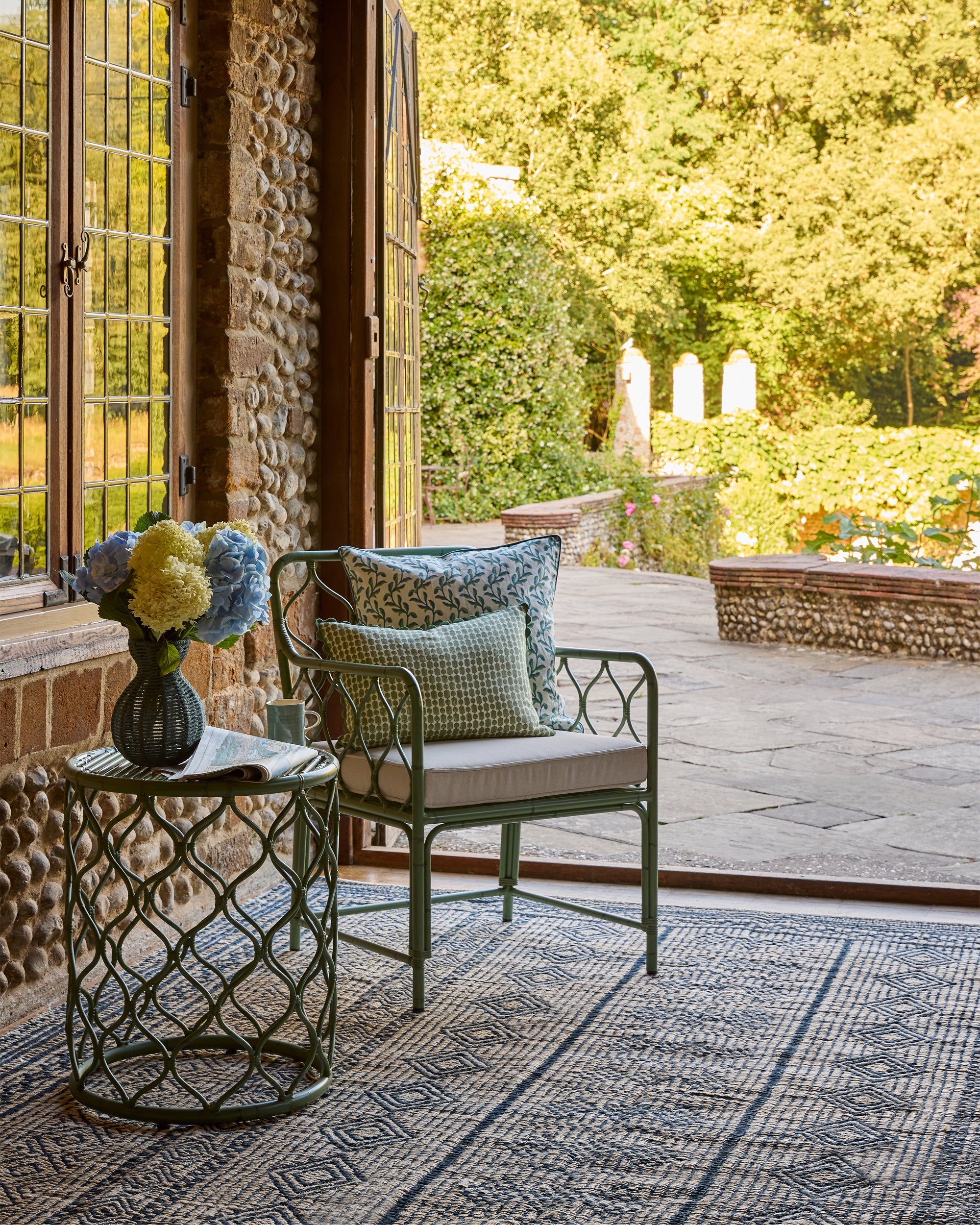 Spring summer lifestyle image featuring our Curato garden furniture,  Moroccan Jute Rug and blue string vase