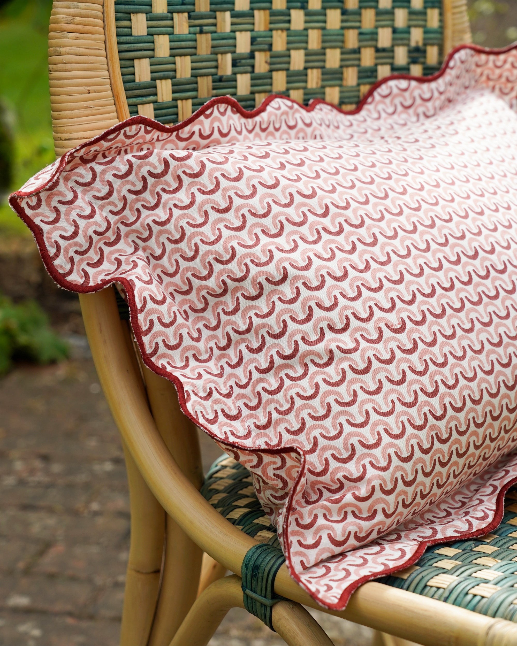 Birdie Fortescue pink teja cushion styled on the green rattan dining chair