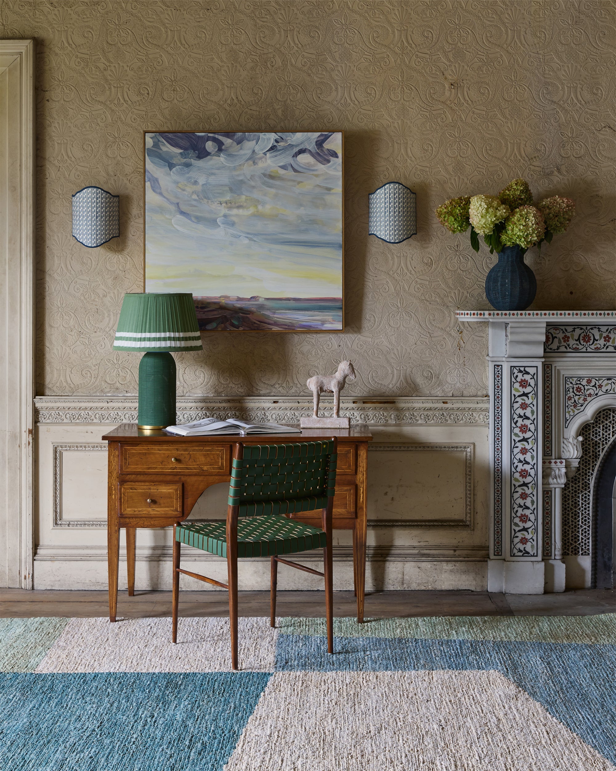 Decorative interior with a desk, chair, lamp, and artwork on a textured wall.