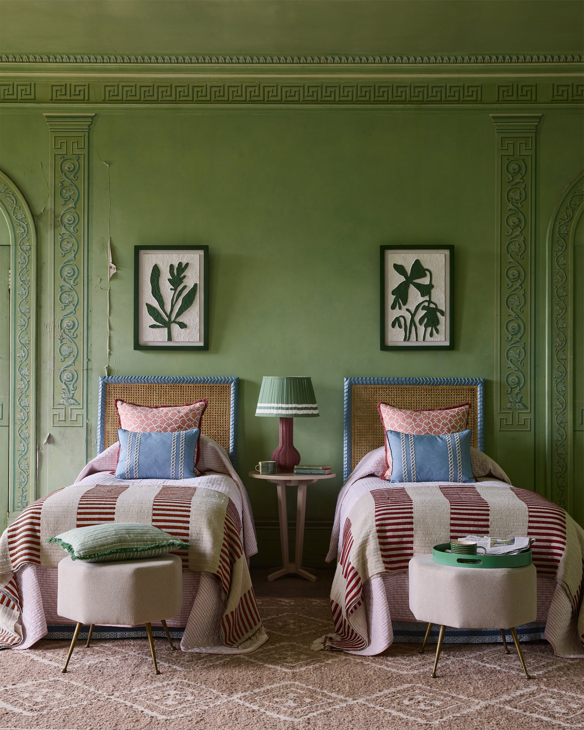 Two twin beds with striped bedding in a room with green walls and decorative molding.