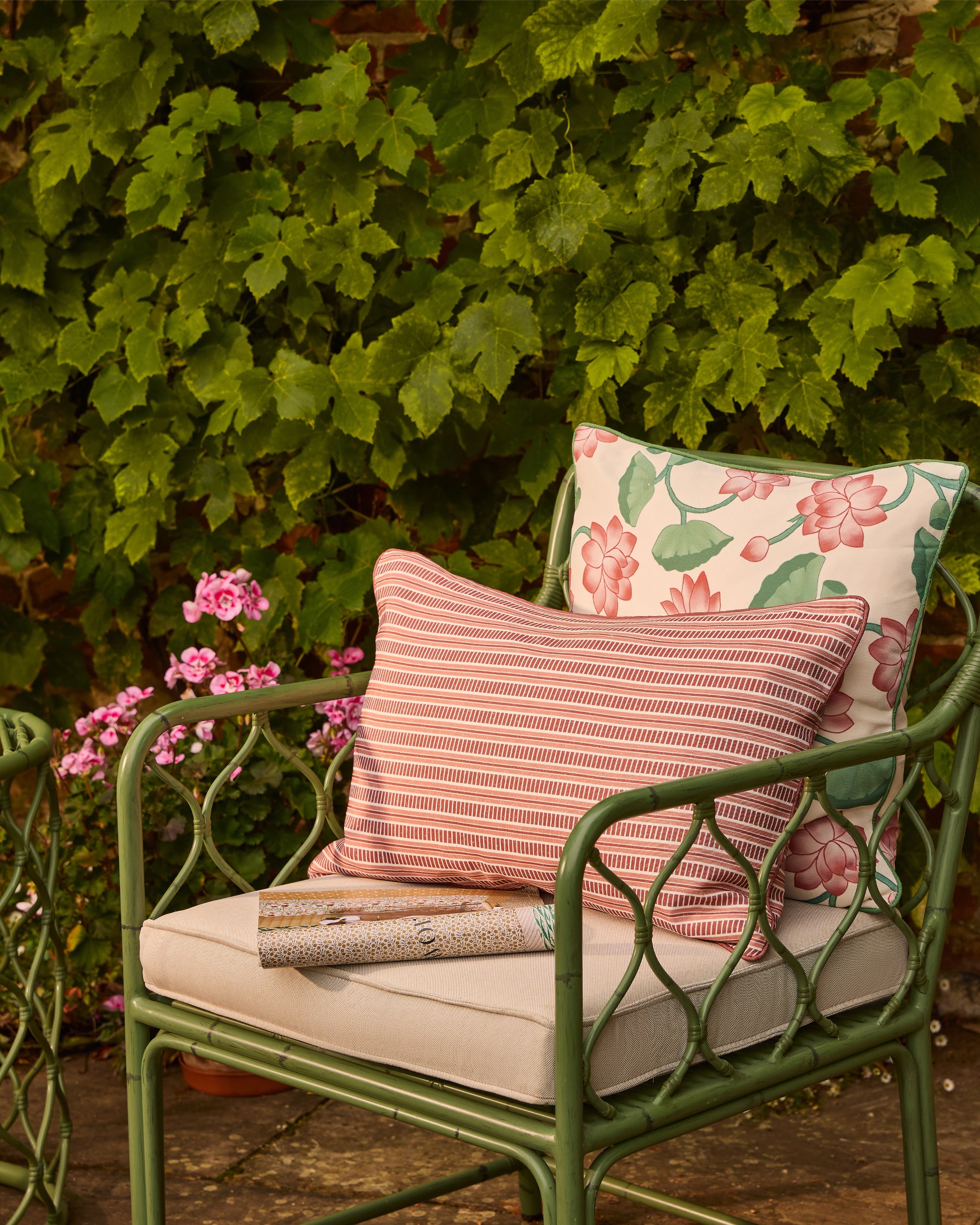 Green chair with floral and striped cushions against a leafy background