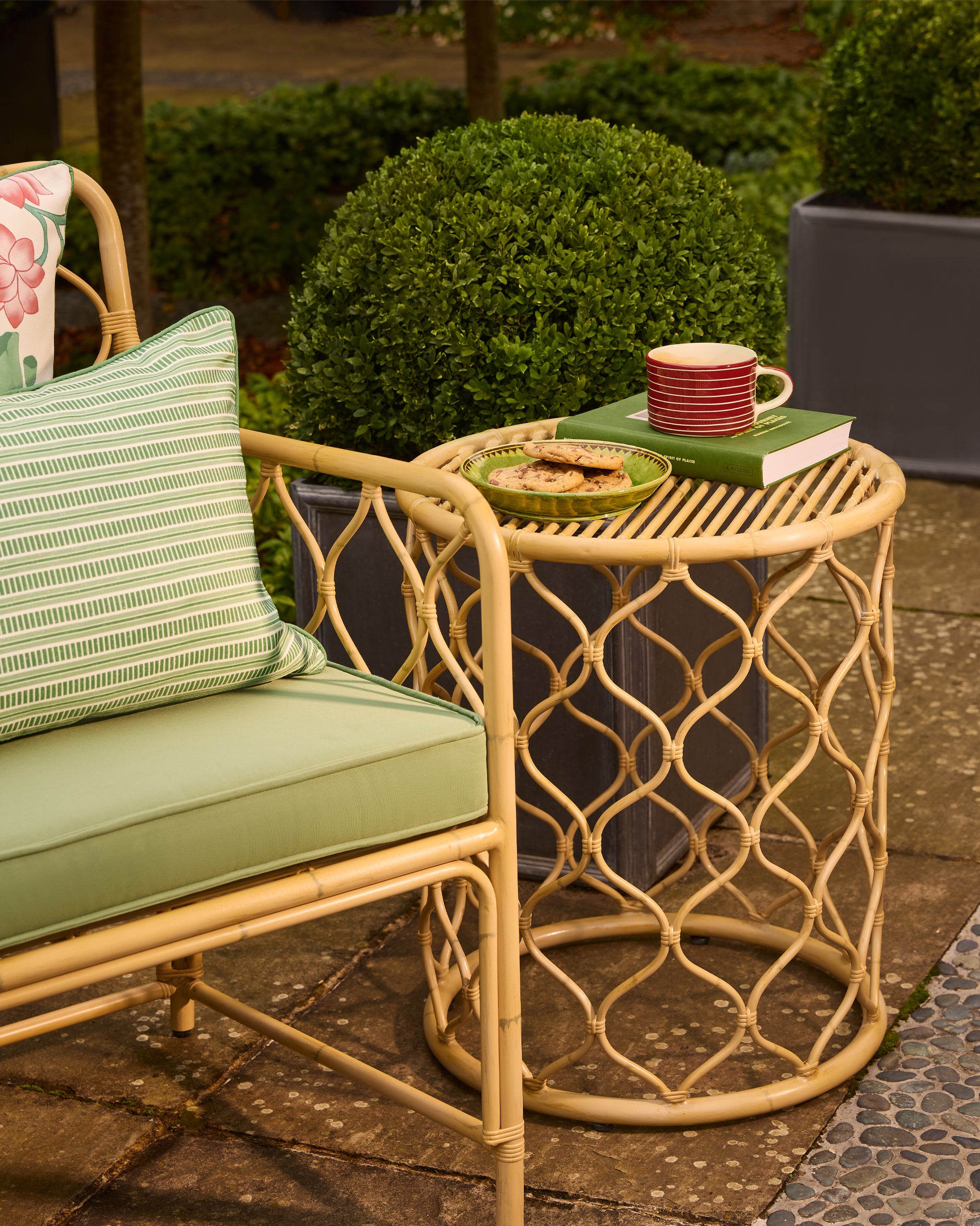 Rattan outdoor furniture set with a small table and cushioned chair on a patio.