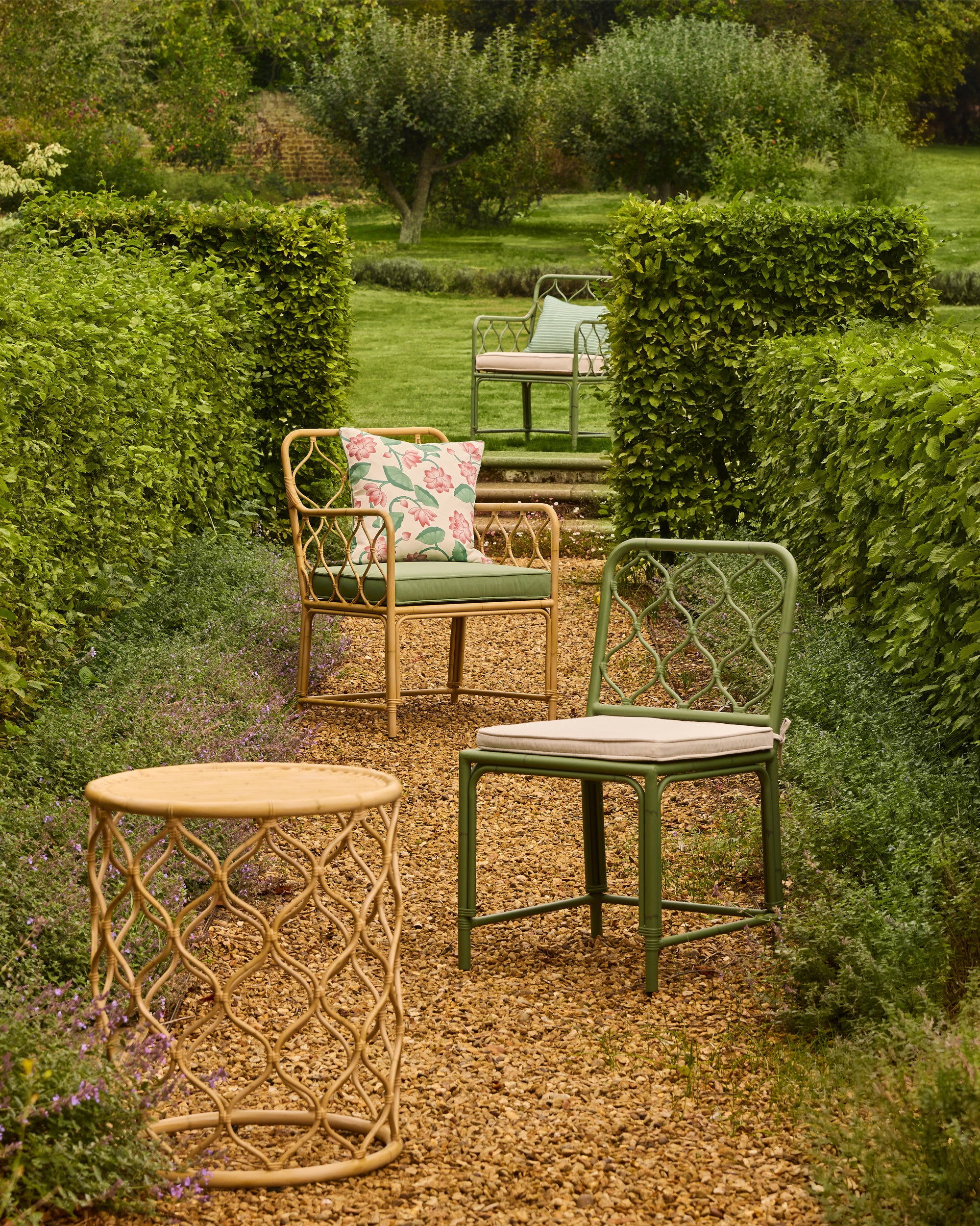 Garden setting with outdoor furniture including chairs and a table, surrounded by greenery.