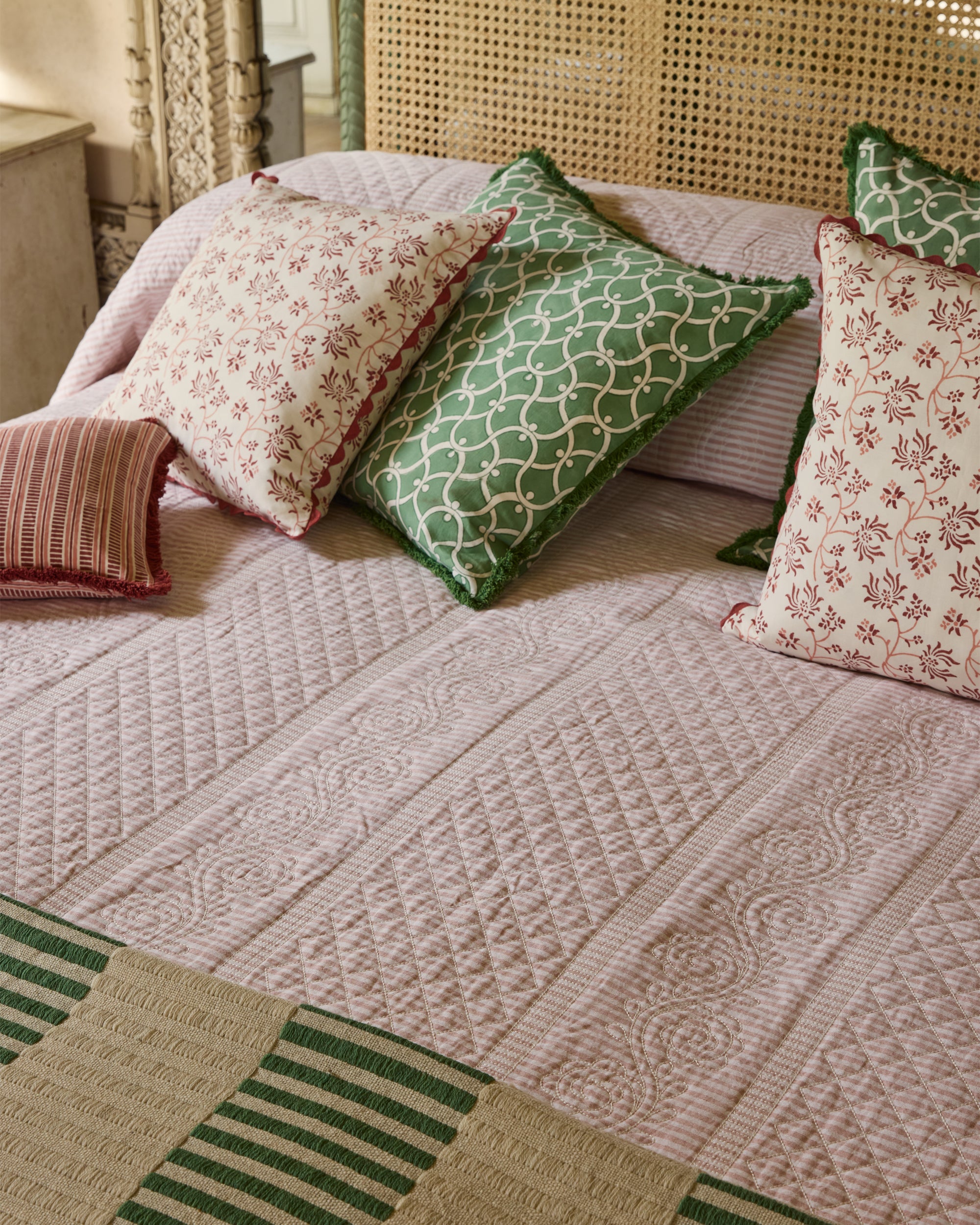 Bed with patterned bedding and pillows in a bedroom setting