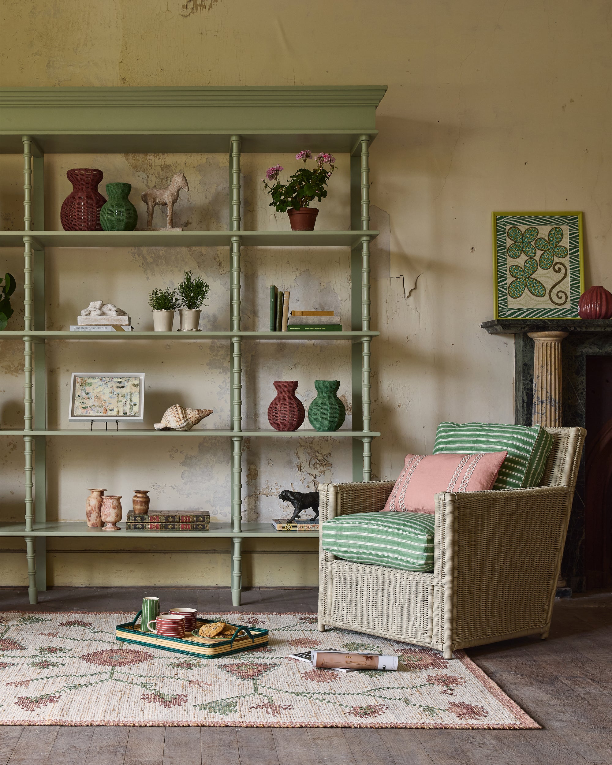 Room interior with a green bookshelf, armchair, and decorative items.