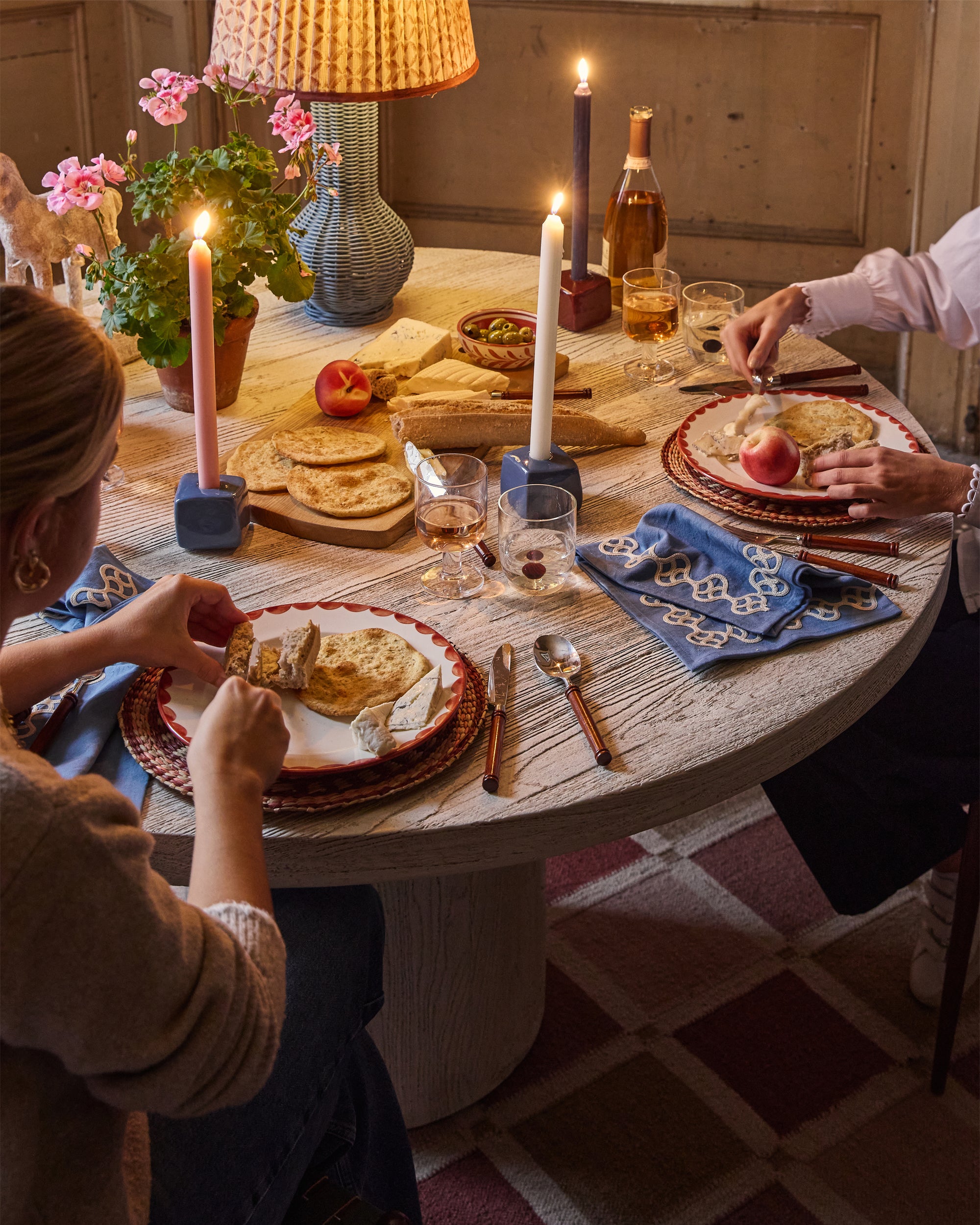 People enjoying a meal around a candlelit table with wine and bread.