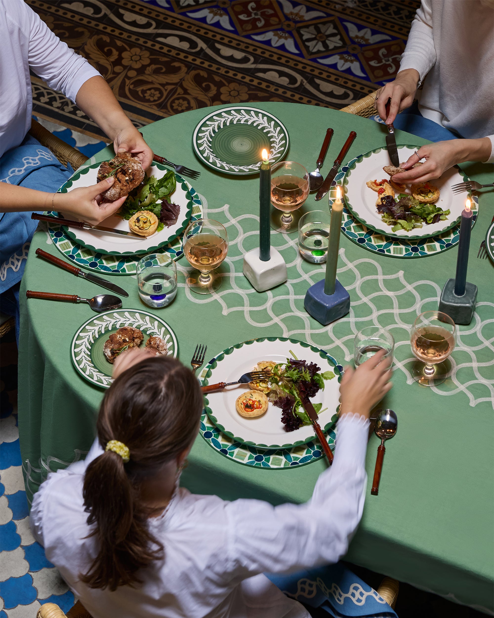People sitting around a table with a meal and drinks on a patterned floor.