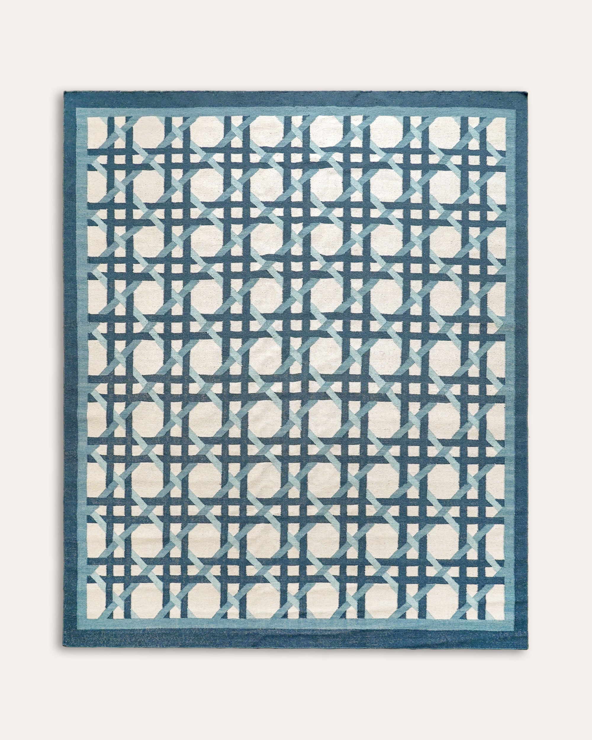 Blue and white geometric patterned rug on a light grey background