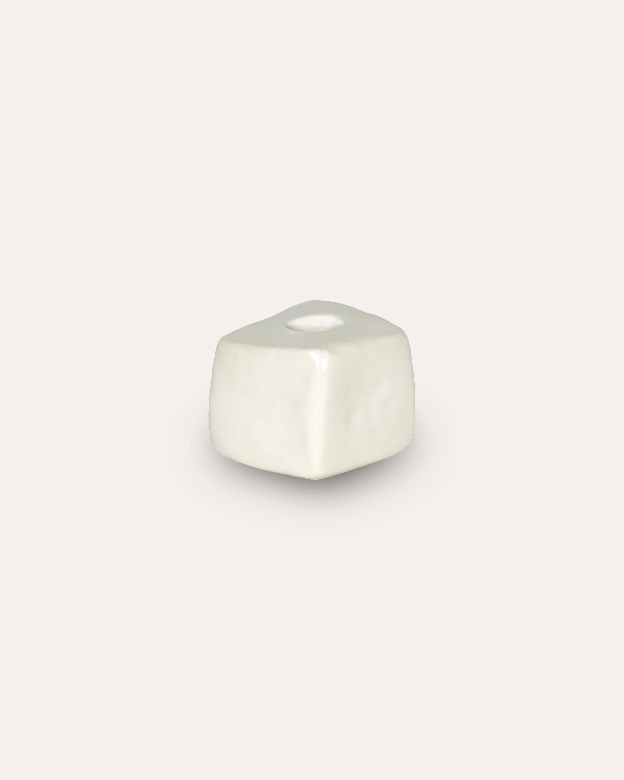 Off-white decorative candle holder on a taupe background