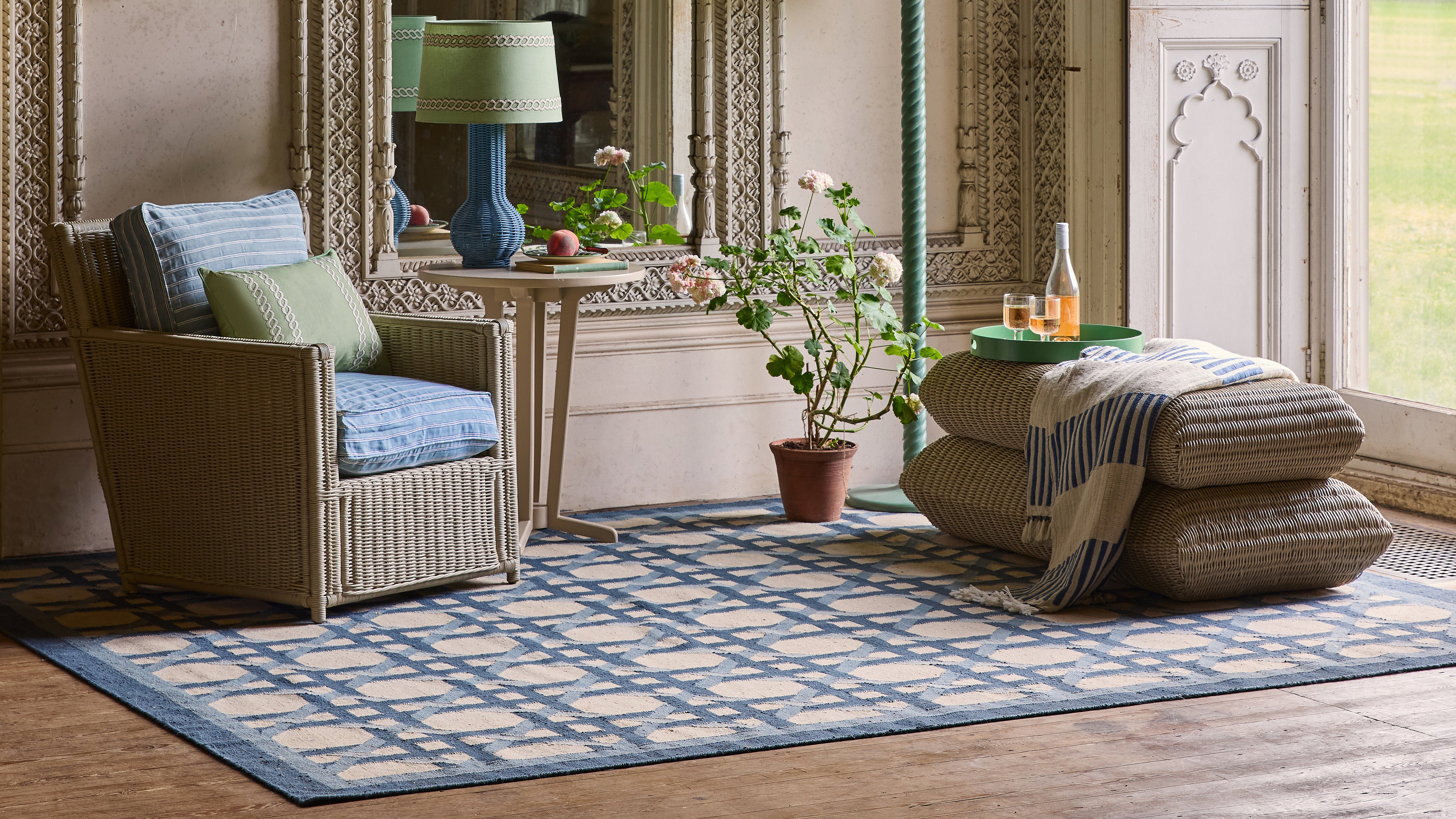 Living room with rattan chair, ottoman, and decorative items on a blue checkered rug.