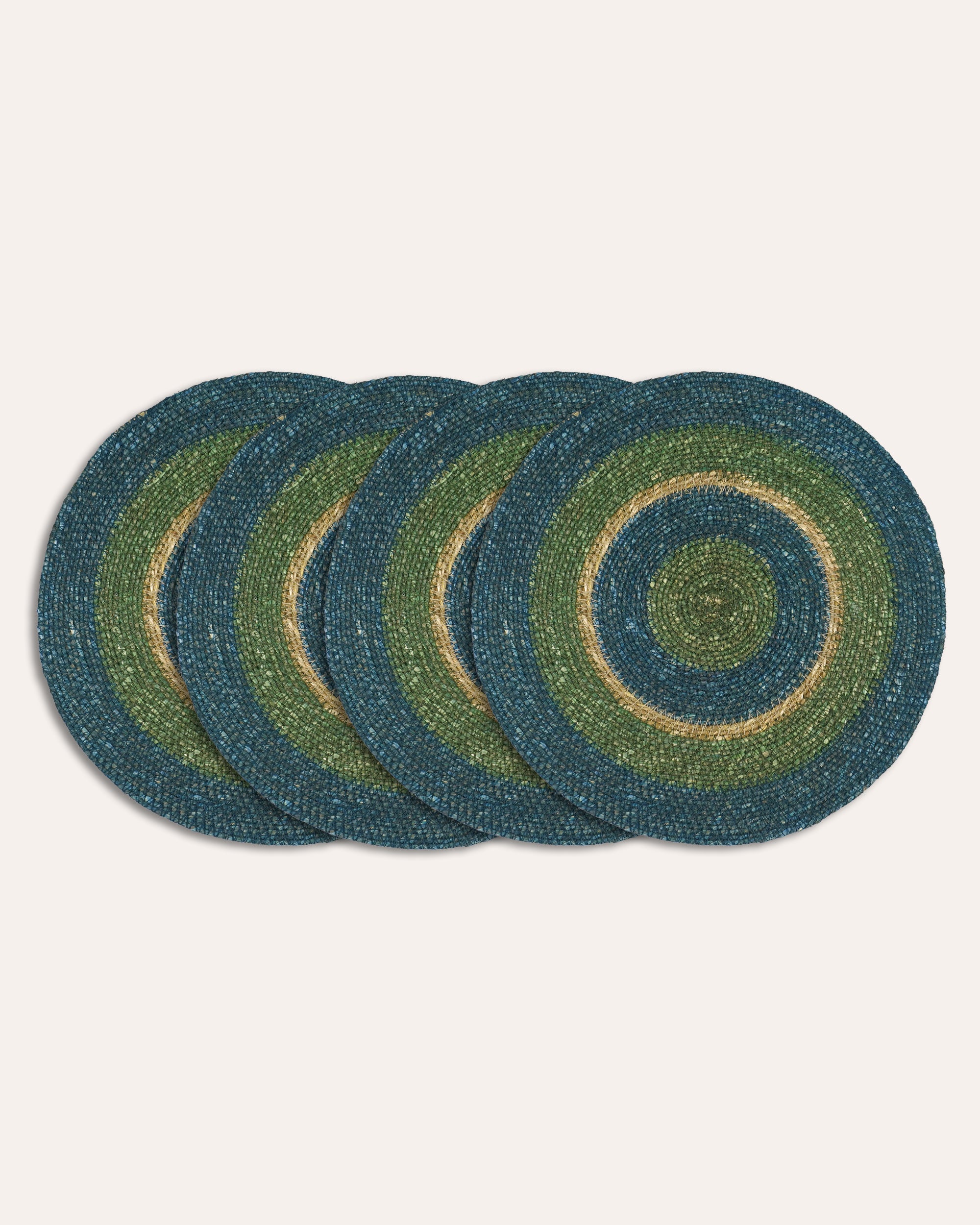 Set of four round woven placemats with concentric circle pattern on a white background