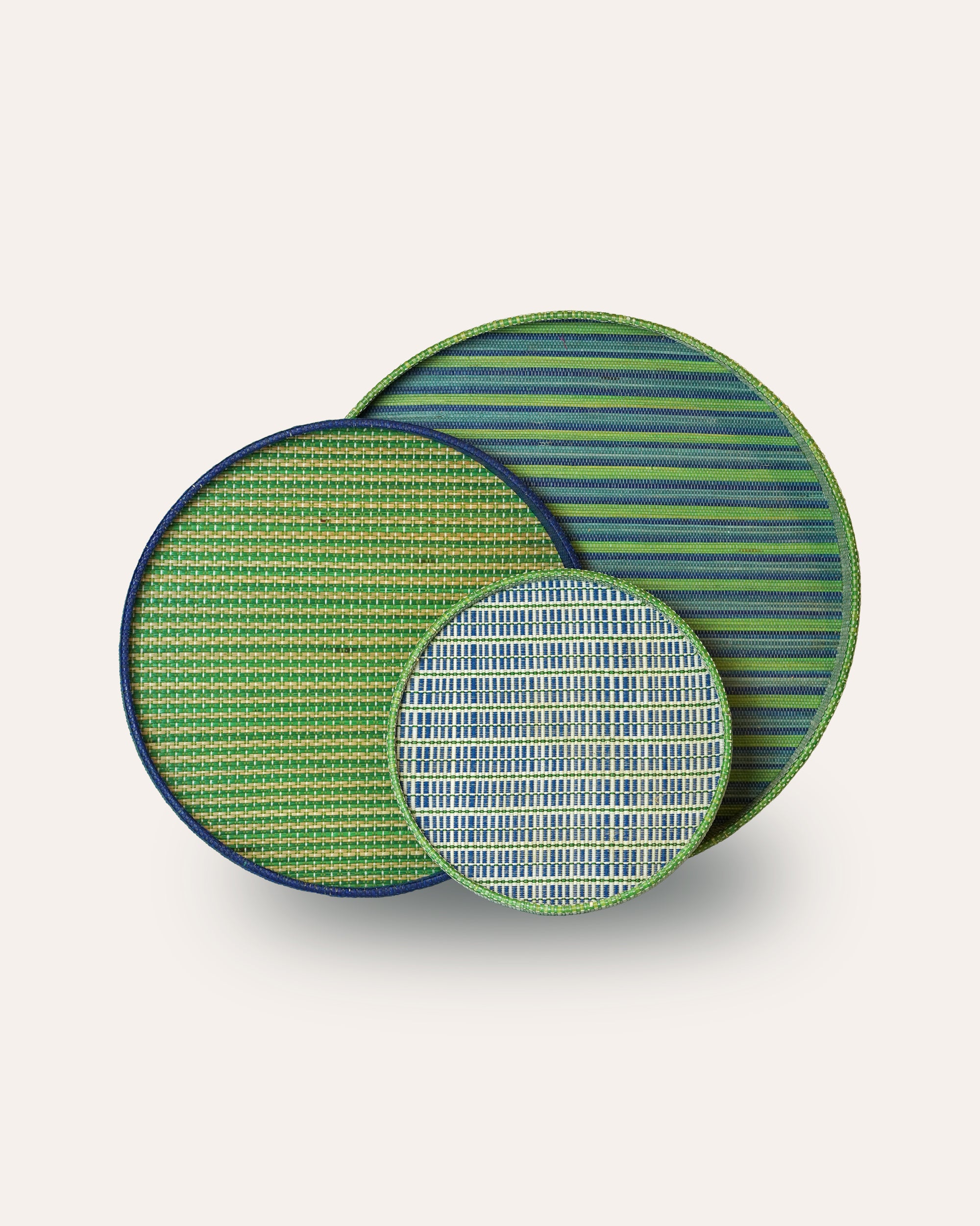 Set of three green and blue striped patterned trays on a white background